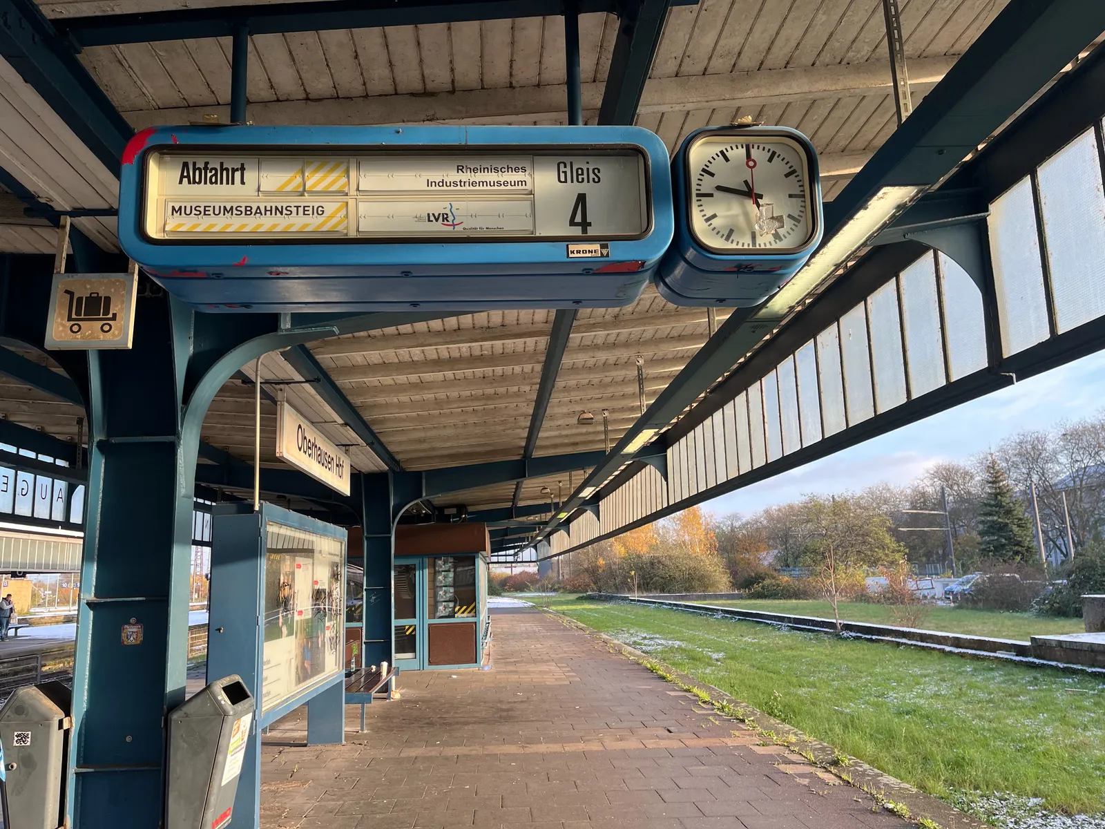 A mechanical display in a deserted train platform in Oberhausen. The display says, in German, that this is the Museum Platform from the Reinisches Industriemuseum. The clock next to the display points at 25 past 9.
