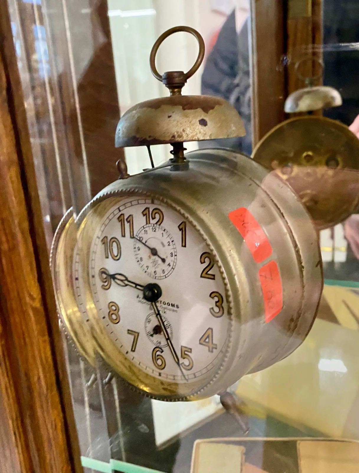 An old mechanical alarm clock with a sinlge bell on top. It points at 26 past 9.