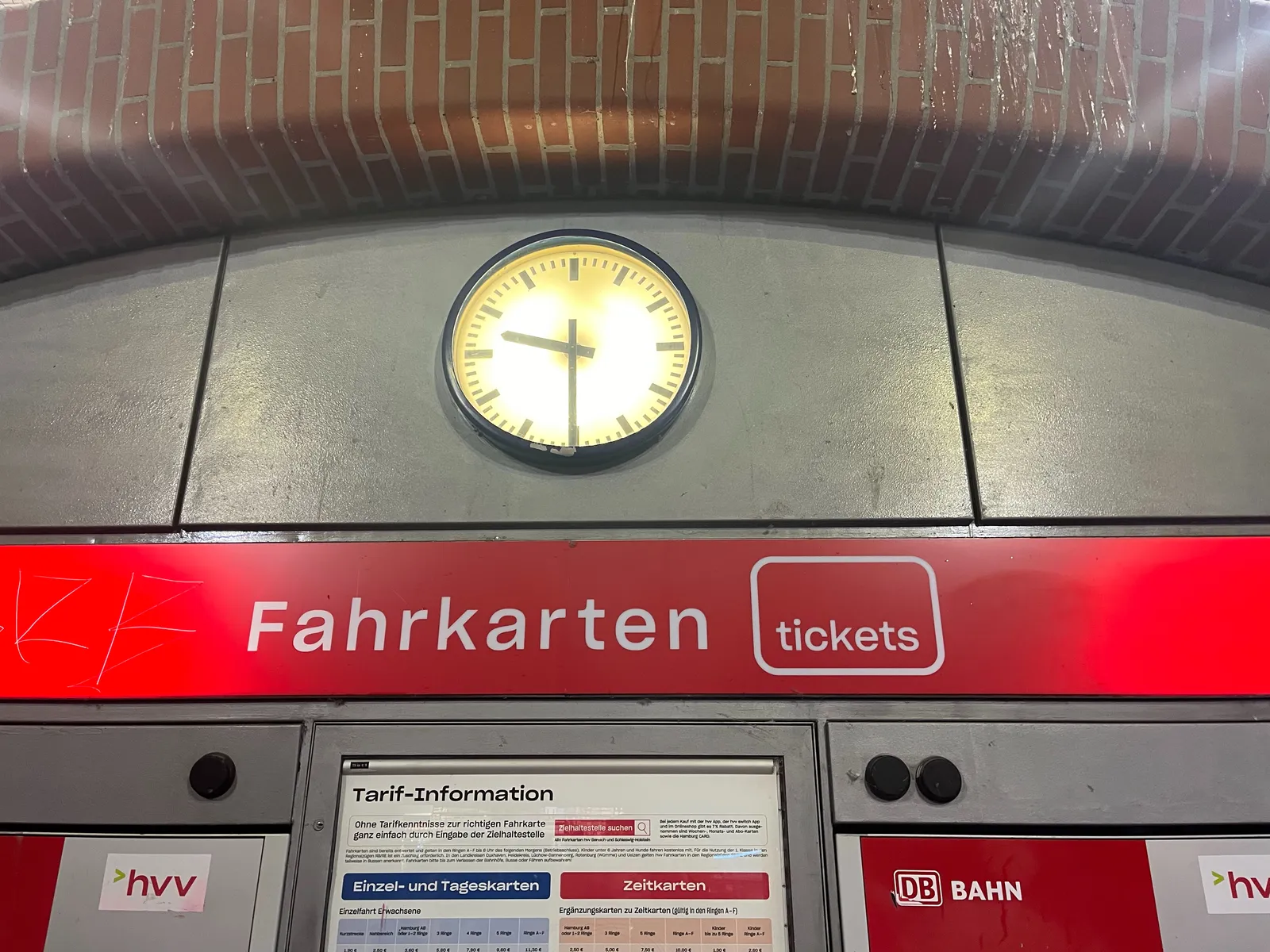 A clock above some ticket vending machines indicates that it is nine thirty.