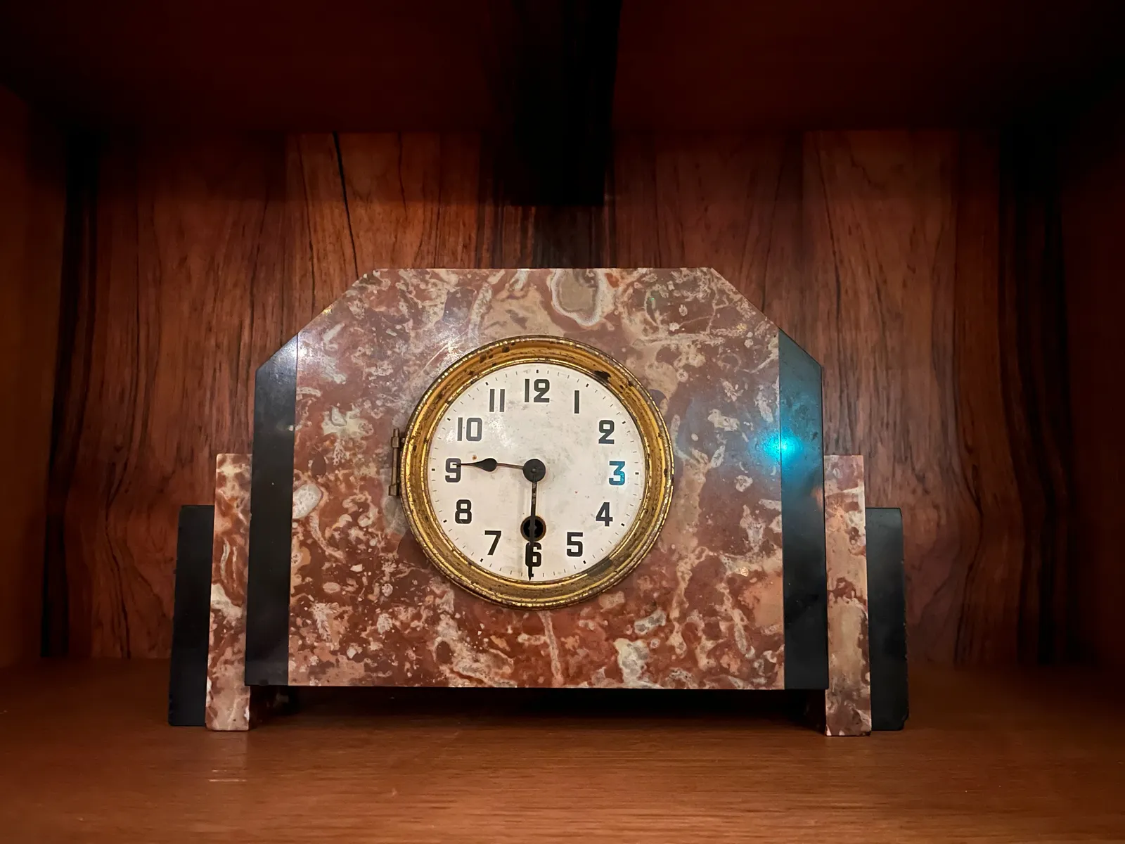 An old brown marble clock. It’s clear that it’s purely ornamental, without the necessary attention to detail: the hour hand points at the whole hour, while the minute hand points down. Let’s just assume that it points at half past nine and forget about it.