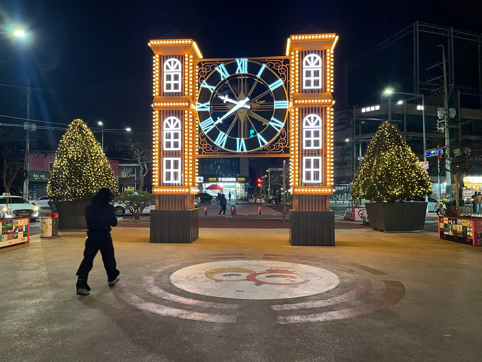 On a square there’s this rather large decoration. It is a brightly lit clock, hanging between two brightly lit towers. The clock points at 21 minutes to 10.