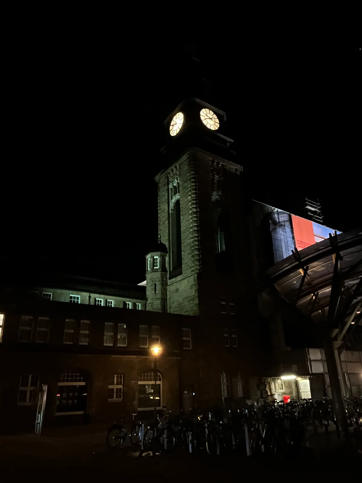 A dark building against a dark sky. According to the lit clock on the building it is 20 minutes to 10.