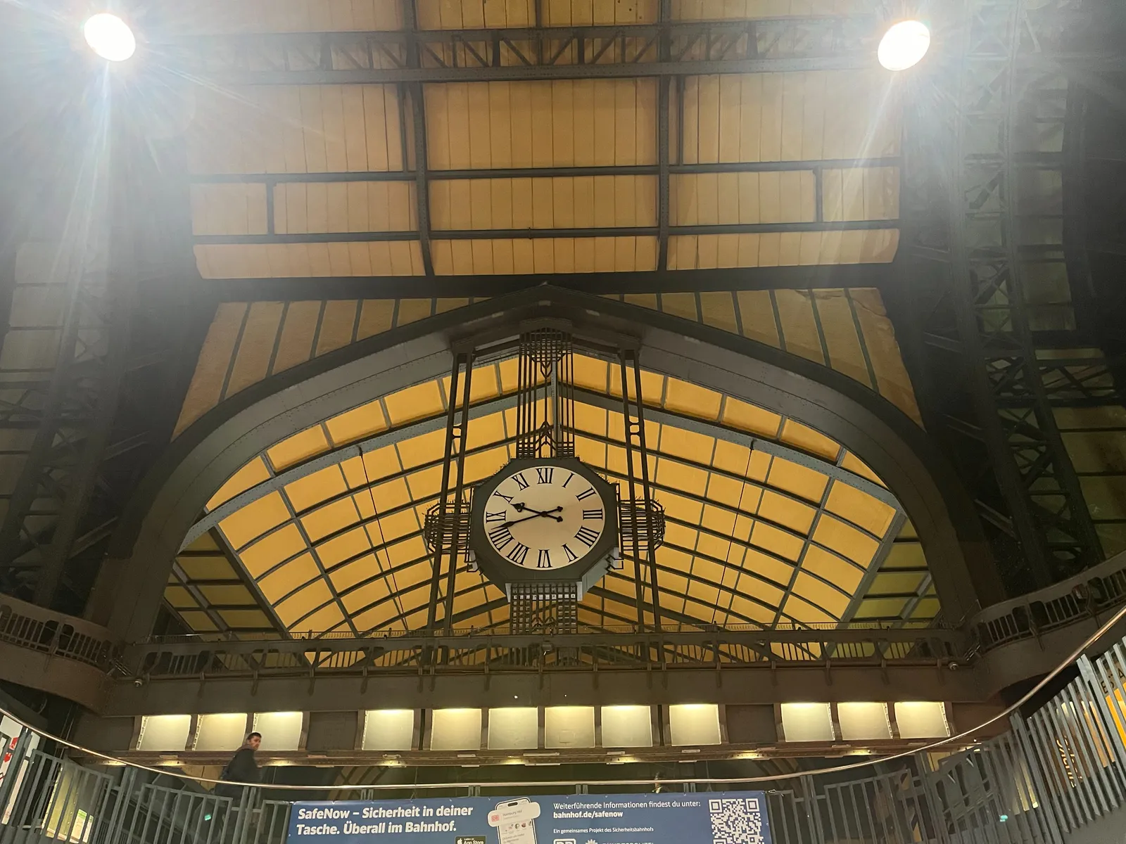 A large clock inside an enormous, old train station. It points at 18 minutes to 10.
