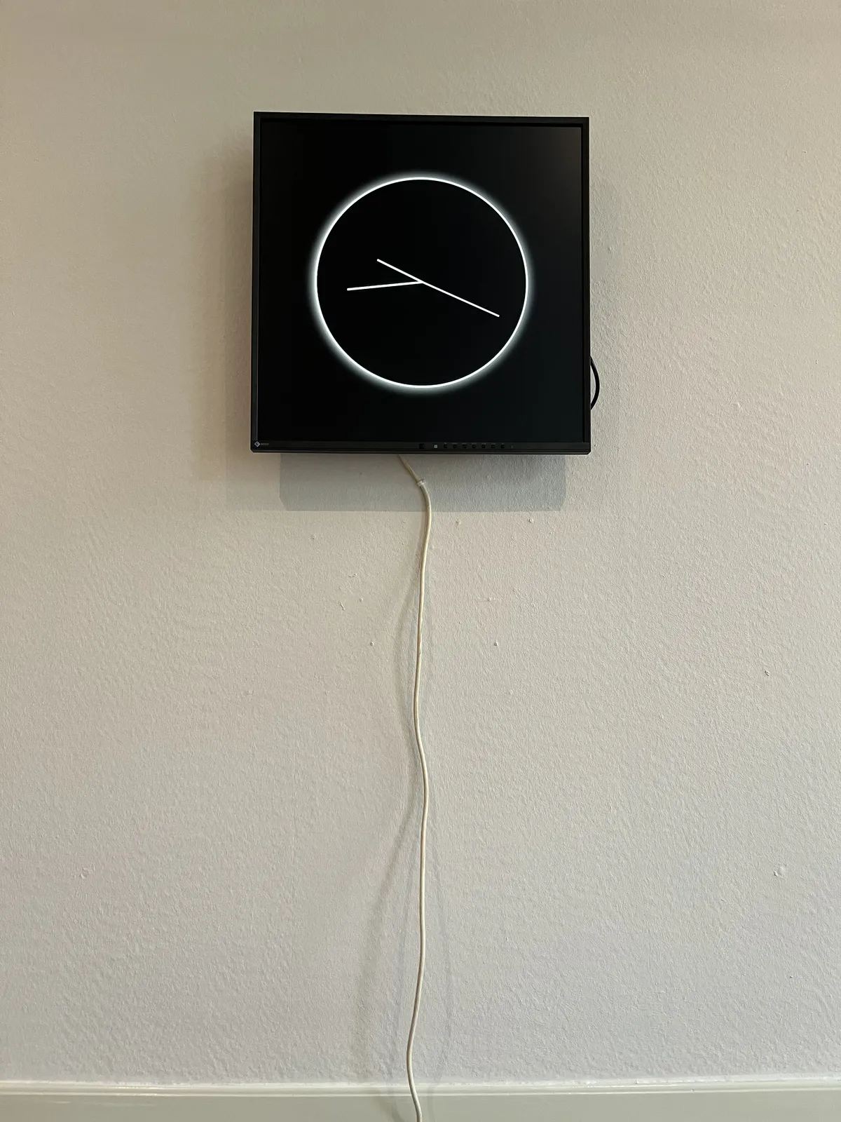 On a black display, a white, very minimalist clock is displayed. I assume that the longest hand is the seconds hand. In that case this clock points at 16 minutes to ten.