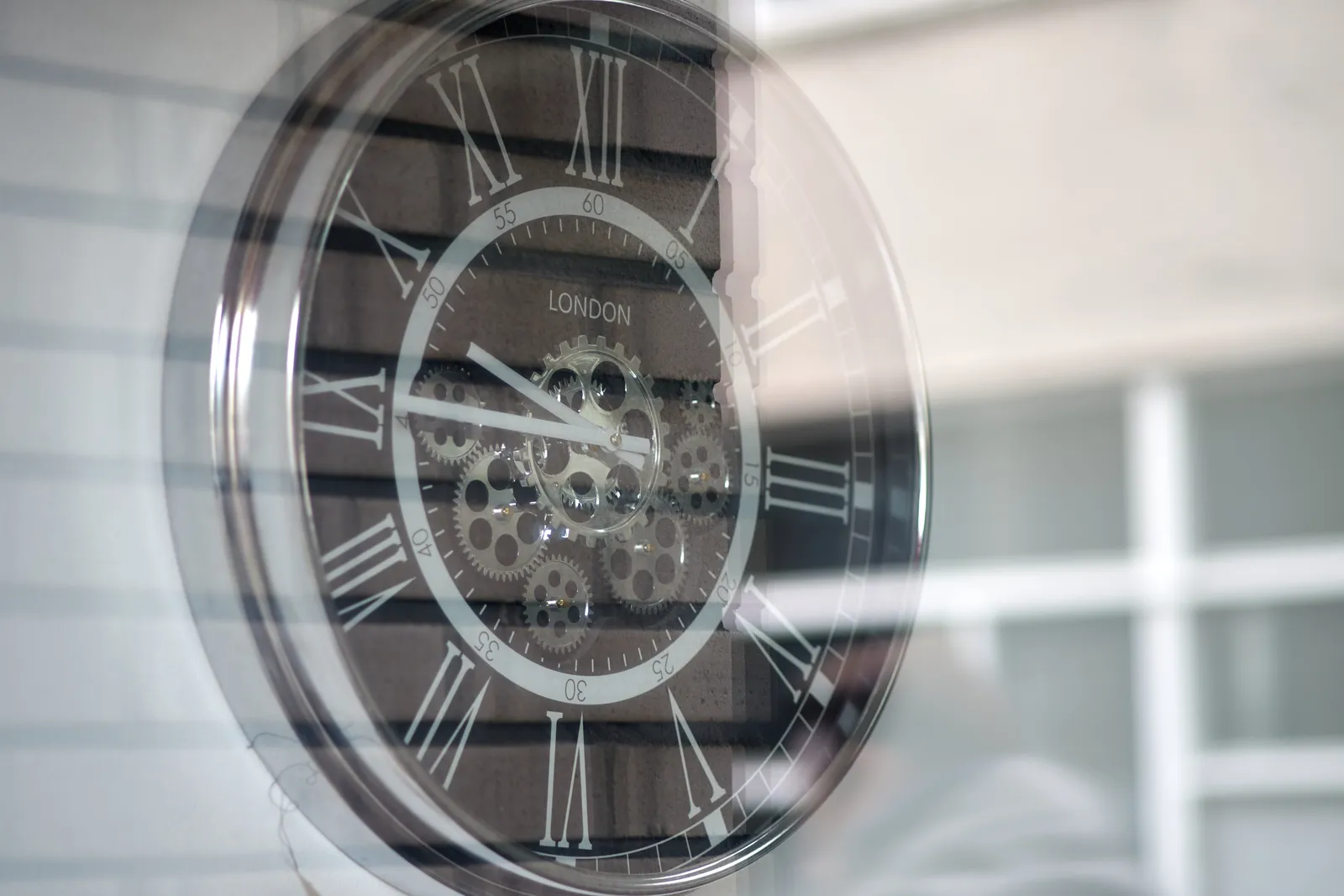 An eclectic clock, shiny plastic, some very visible cogs in the center, and roman numbers. It points at a quarter to ten.