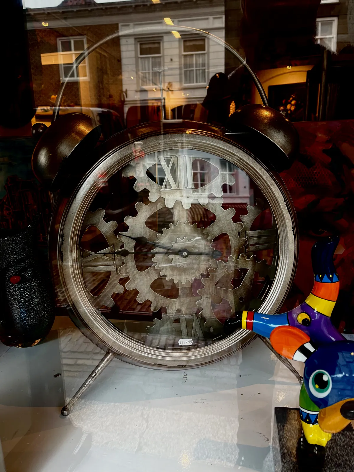 A large rather brutalist alarm clock in a shop window points at a quarter to ten.