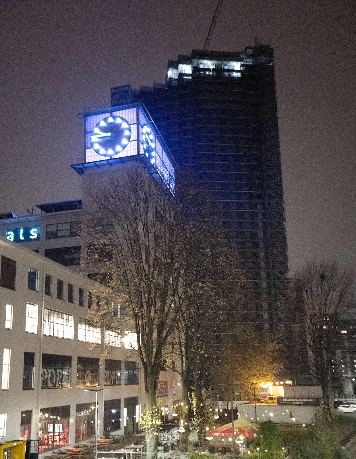 An enormous clock on top of a monumetal building. The clock is lit in blue/purple light. It points at 14 minutes to 10.