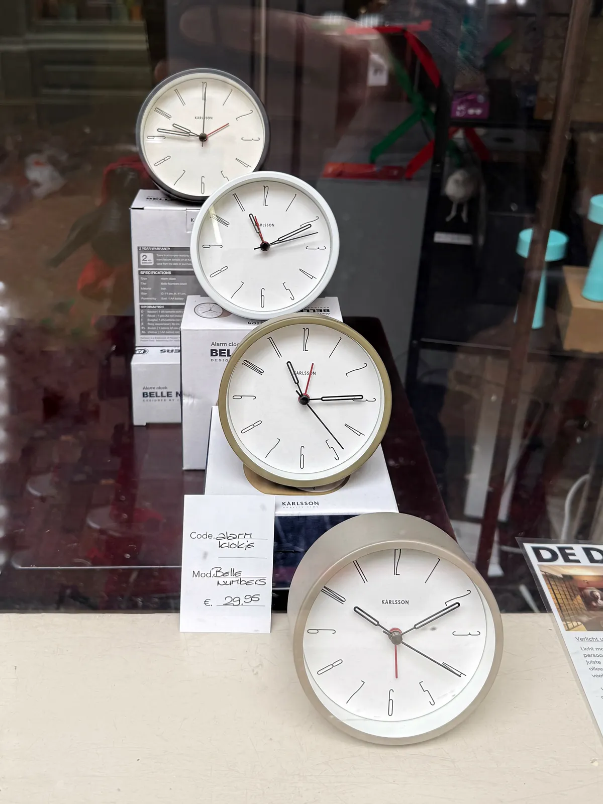 There are four similar alarm clocks standing behind each other. The one in the back points at 14 minutes to ten. The one in the front to ten past ten. The clocks in the middle point at 10 minutes past eleven, and at 14 minutes past eleven.