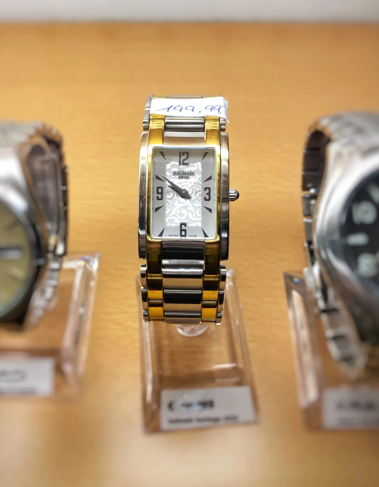 A small rectangular wrist watch. It points at 9 minutes to 10.