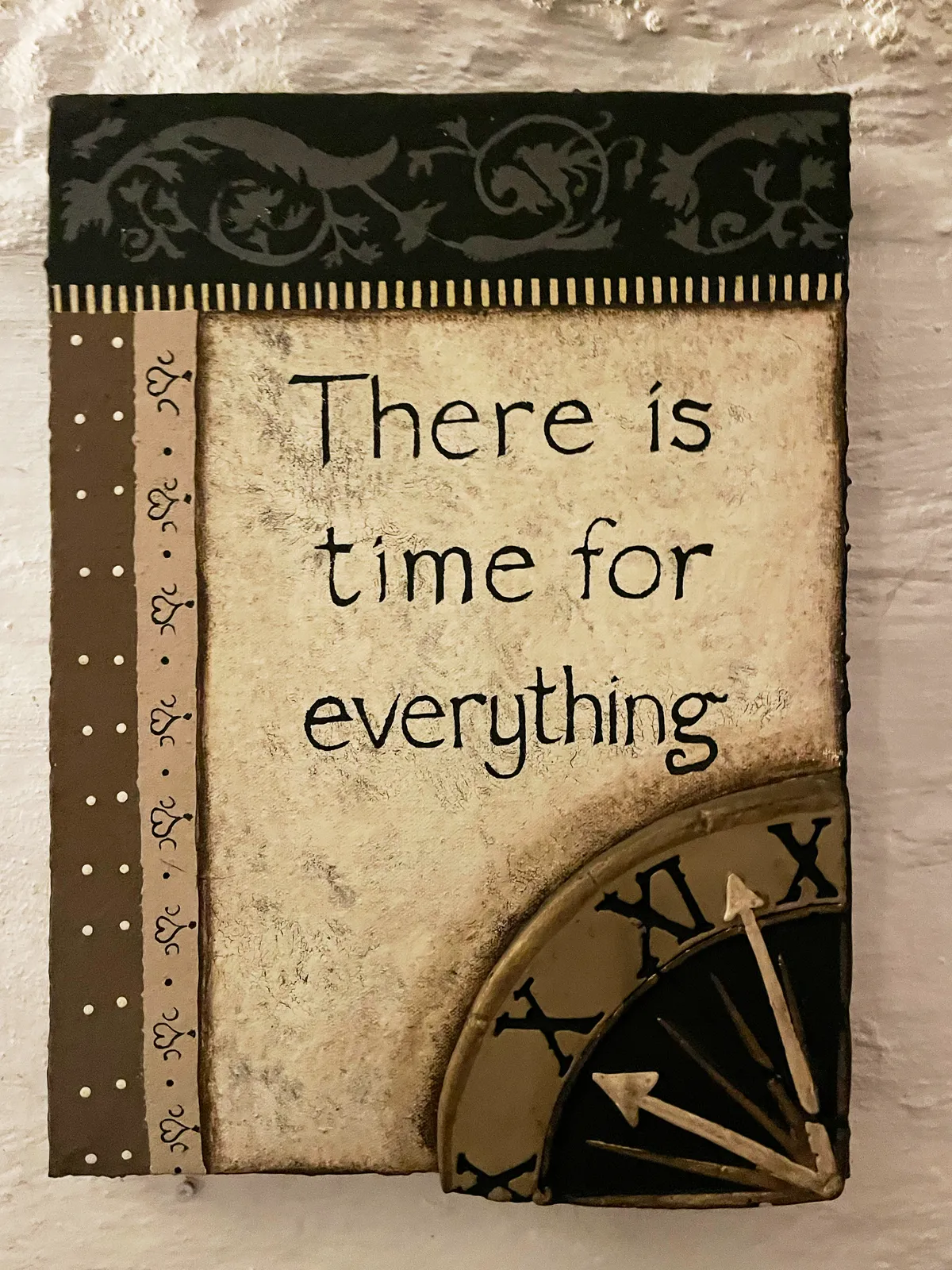 This frame says There is time for for everything. There are some ornaments next to this quote, and the top left corner of a clock can be seen. It points at 3 minutes to ten.