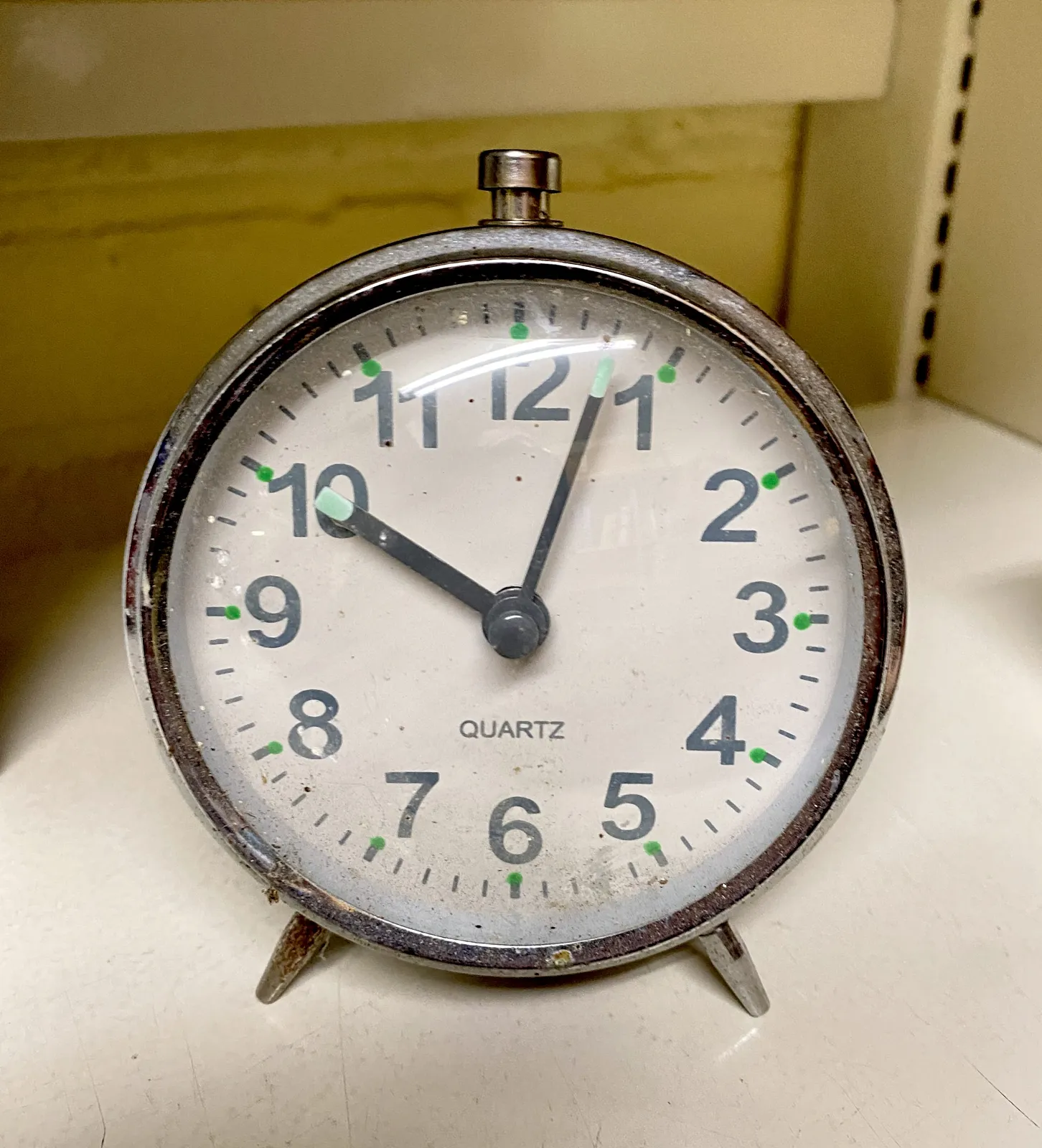 An old, simple mechanical alarm clock. It points at 3 past 10.