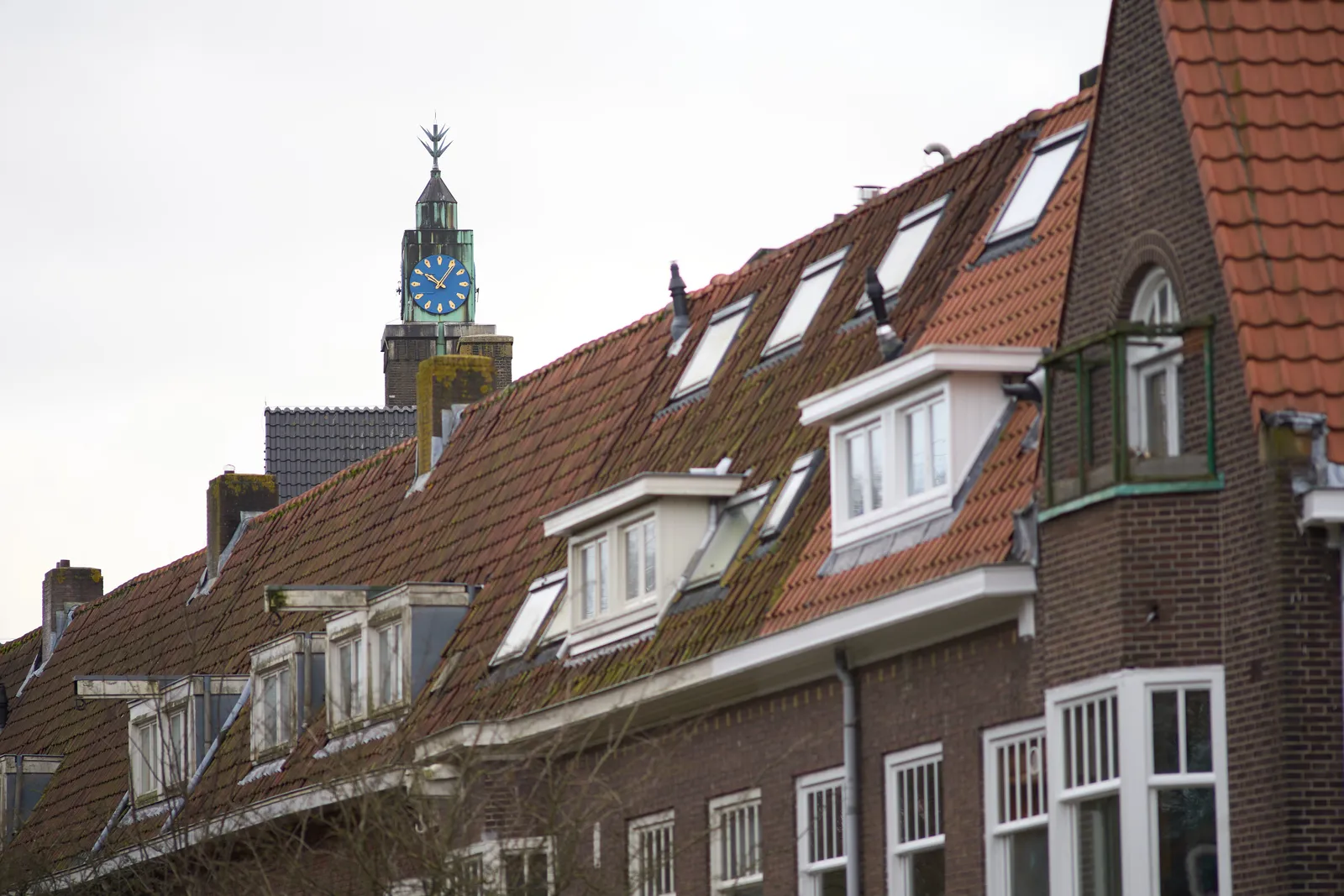 A rather strange, of maybe modern, church tower peeks over a row of houses. The clock points at 5 minutes past 10.