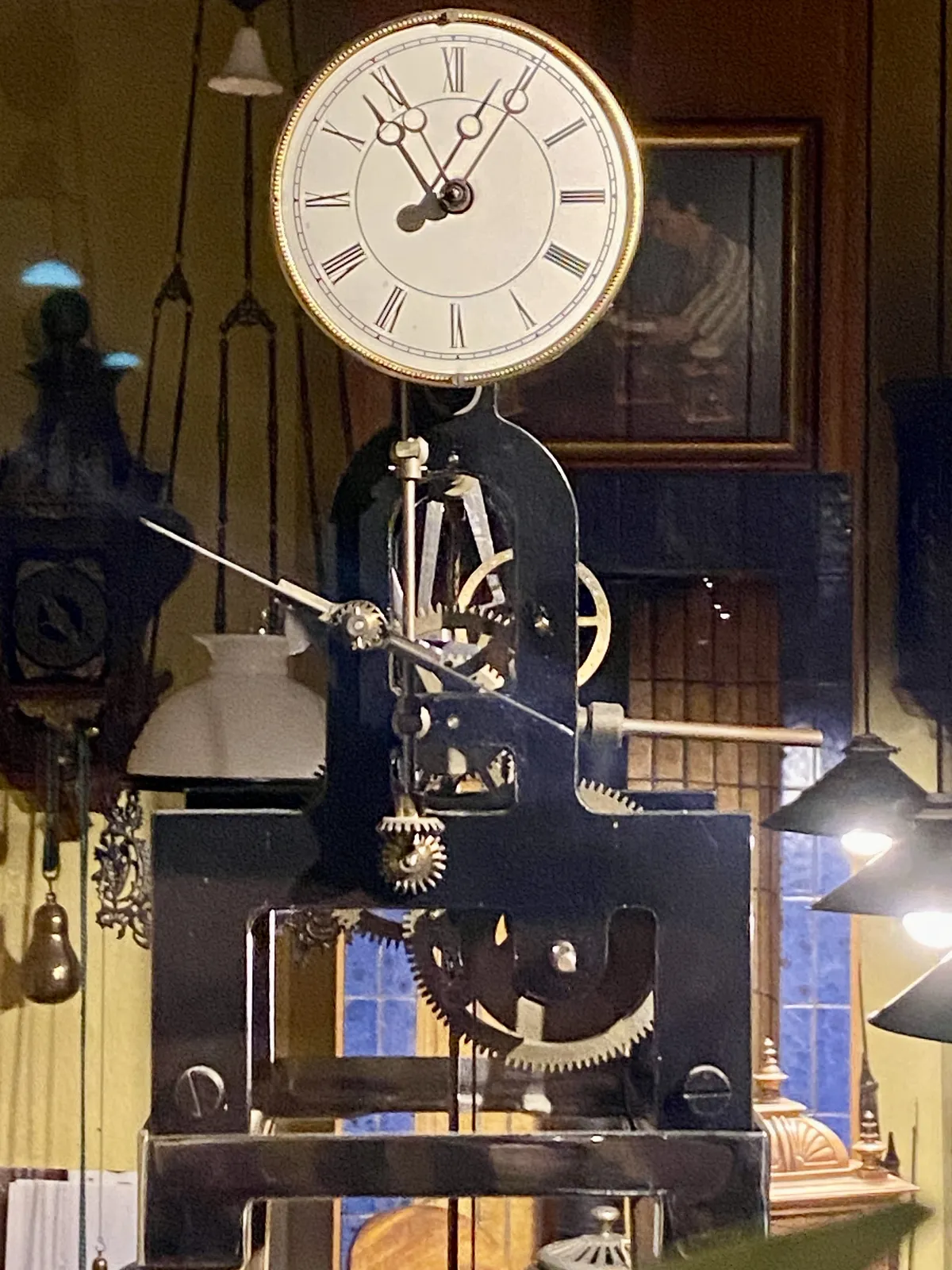 The inner workings of this old mechanical clock, are clearly visible. The housing is removed. The elegant face with thin hands is still attached to it.  It points at 5 past 10.