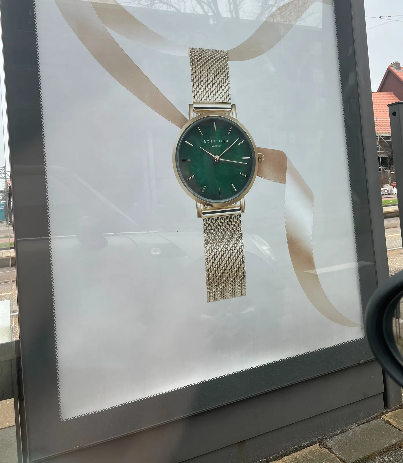 An advertisement on a bilboard for a watch. It’s unclear what time it is, since it’s impossible to say, on this still image, which is the minute hand, and which is the second hand. So it could be 8 minutes past 10, or 16 minutes past 10.