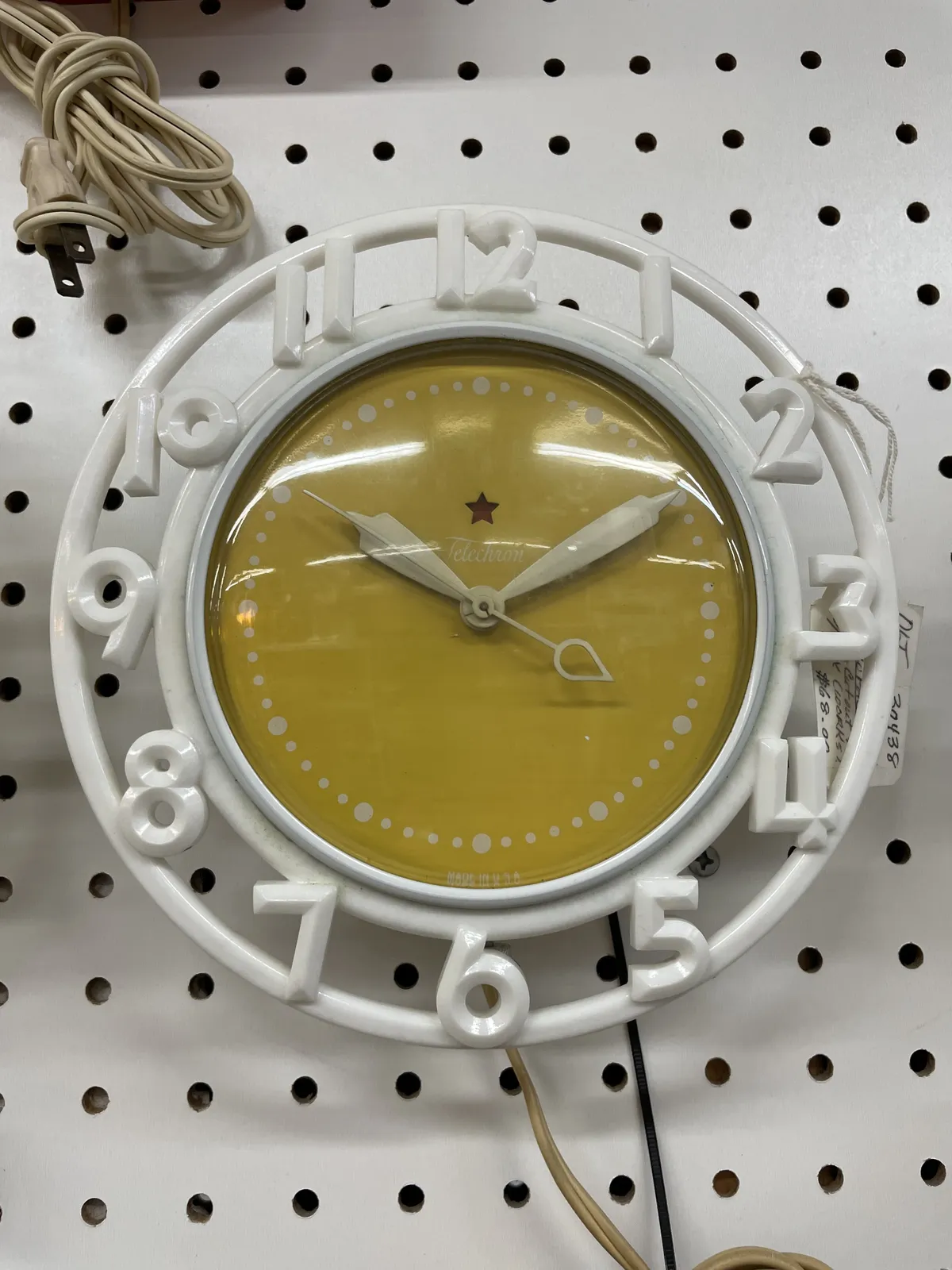 A yellow clock with white numbers, and white circles. The clock points at 10 past 10.