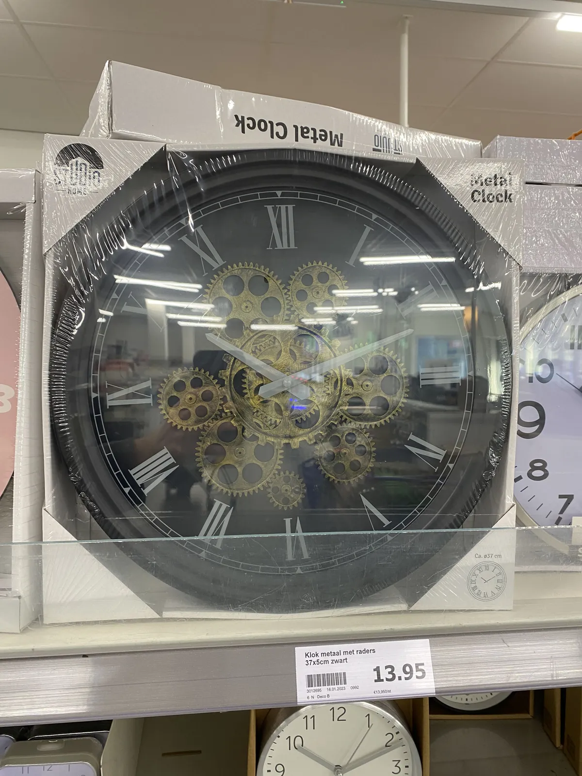 A clock in a box, for sale for 13,95, points at 11 past 10.