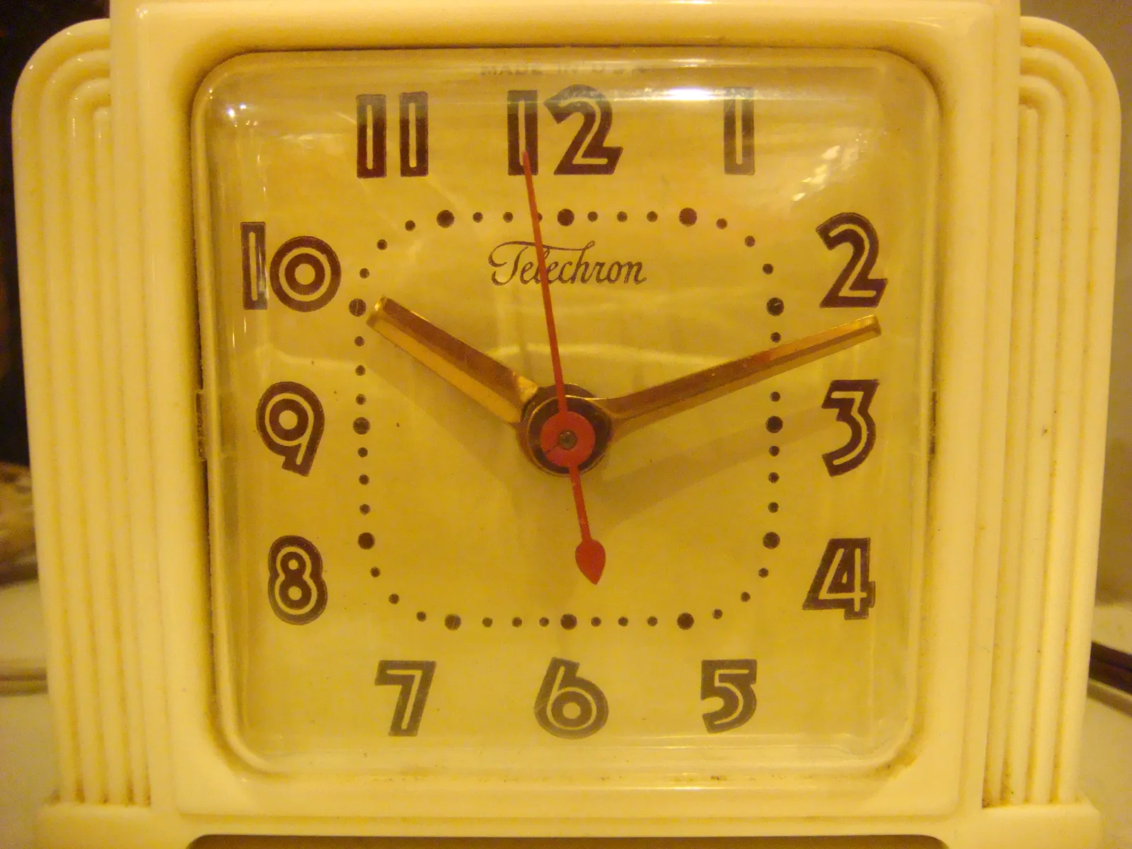 An art deco-ish, white desk clock. It points at 12 minutes past 10.