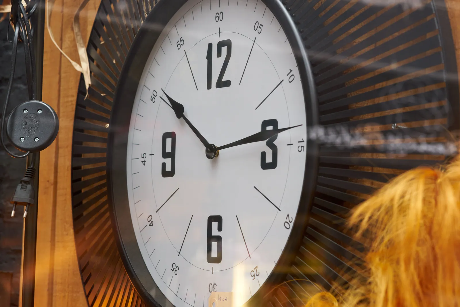 A clock in a shopping window points at 14 past ten.