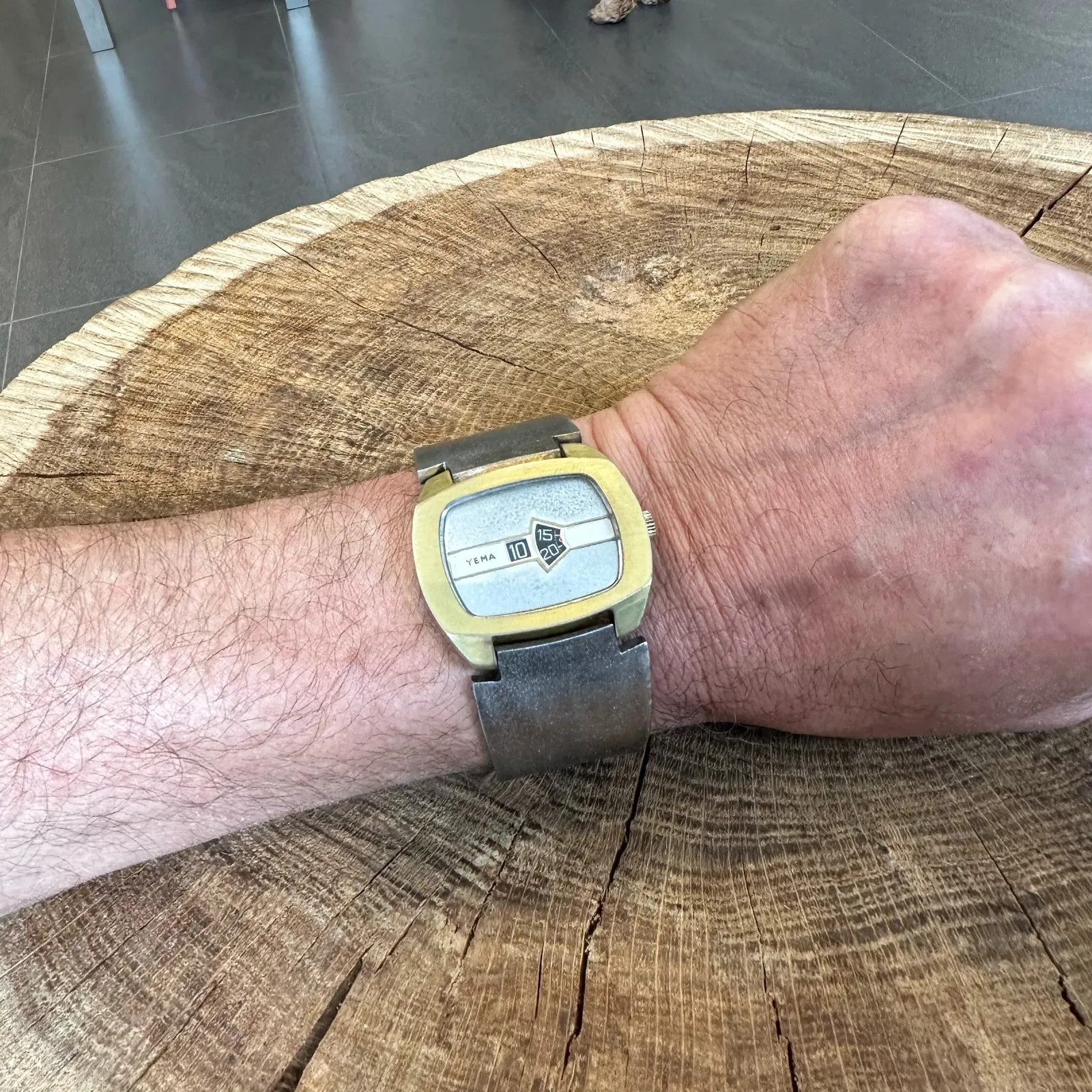 A very special, well designed, elegant, silver and gold, wrist watch on someone’s wrist. The time is not shown by hands, but by two mechanical dials underneath the face. They tell the time as 17 minutes past 10.
