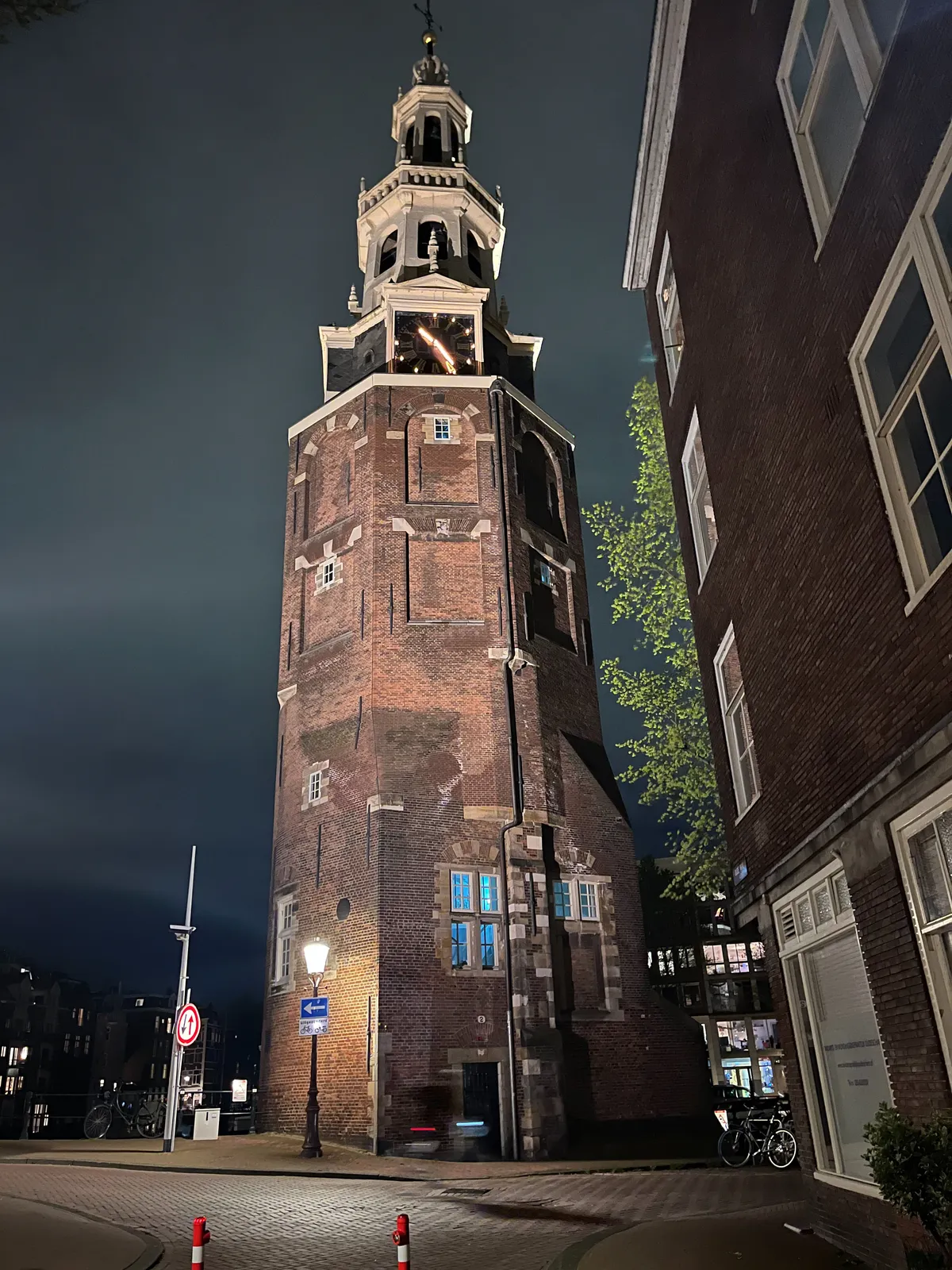 An old church tower with a lit clock on it. It points at 24 minutes past 10.