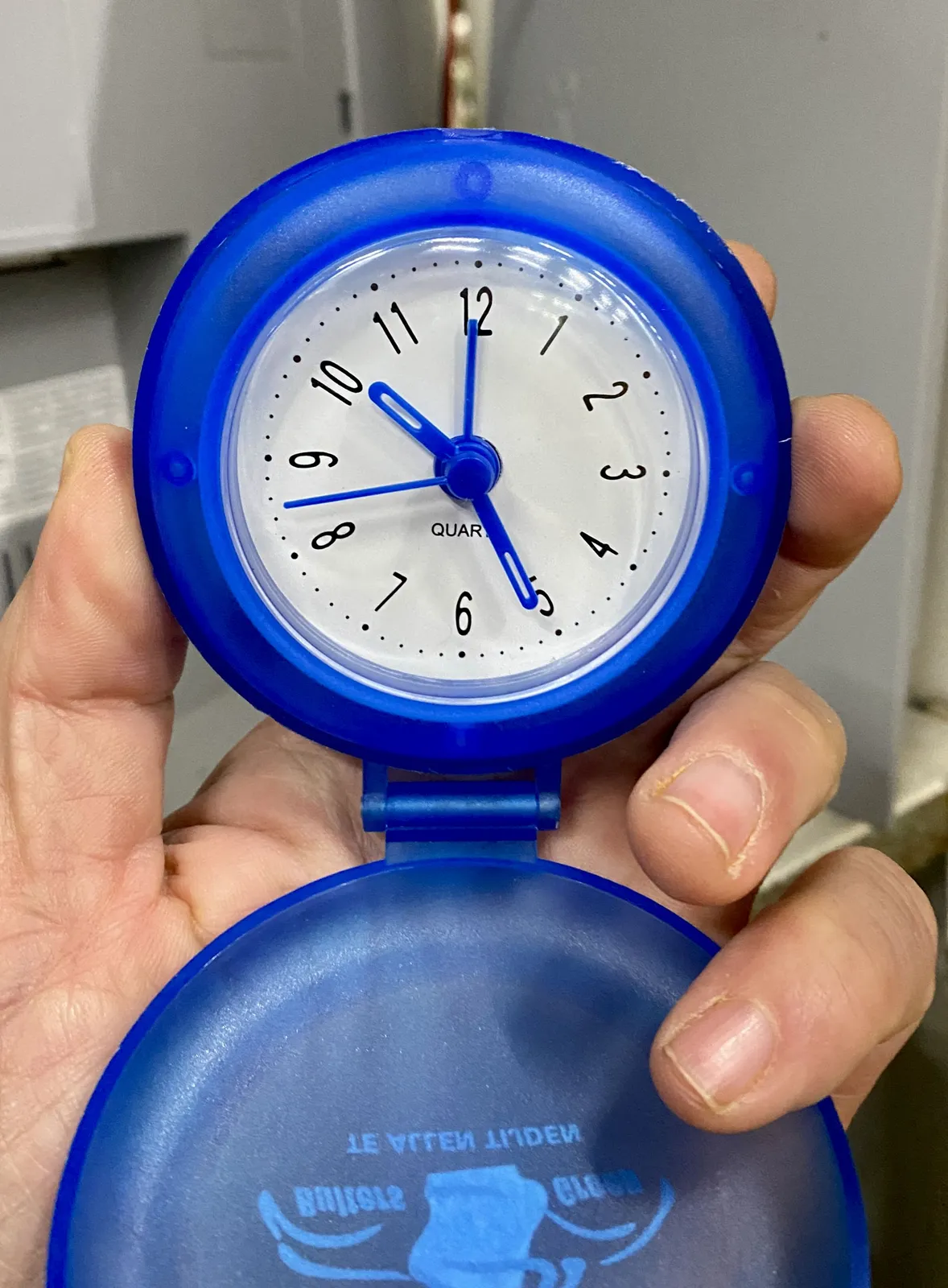 Somebodu is holding a bright blue clock. It points at 26 past 10.