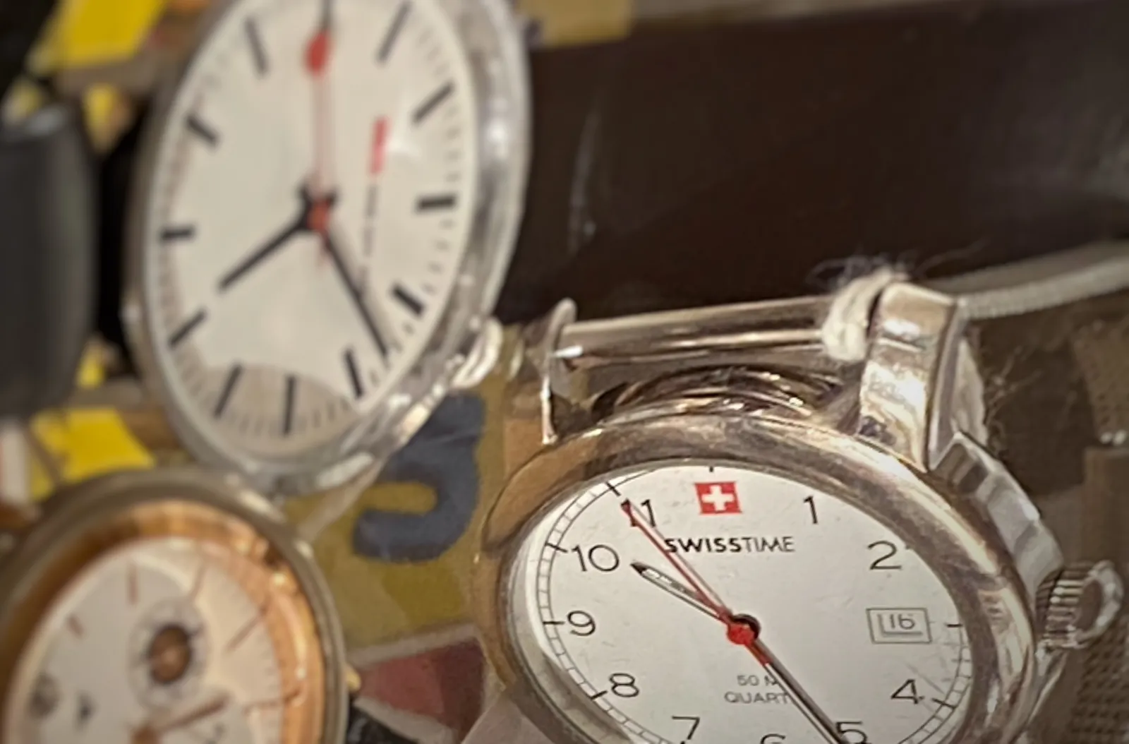 Three watches, only one of them is in focus. It points at approximately 26 minutes past 10. 