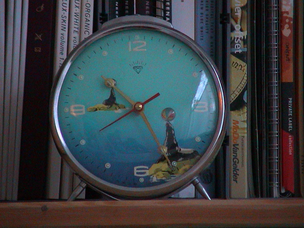 It is 10:26 on the clock with two seals printed on it, balancing a ball on their nose.