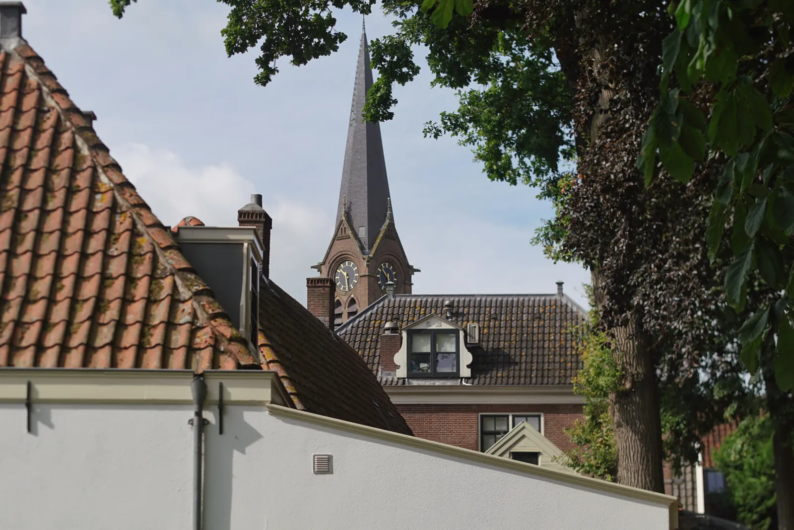 Behind some old houses there’s an old church tower with a clock that points at 29 past 10.