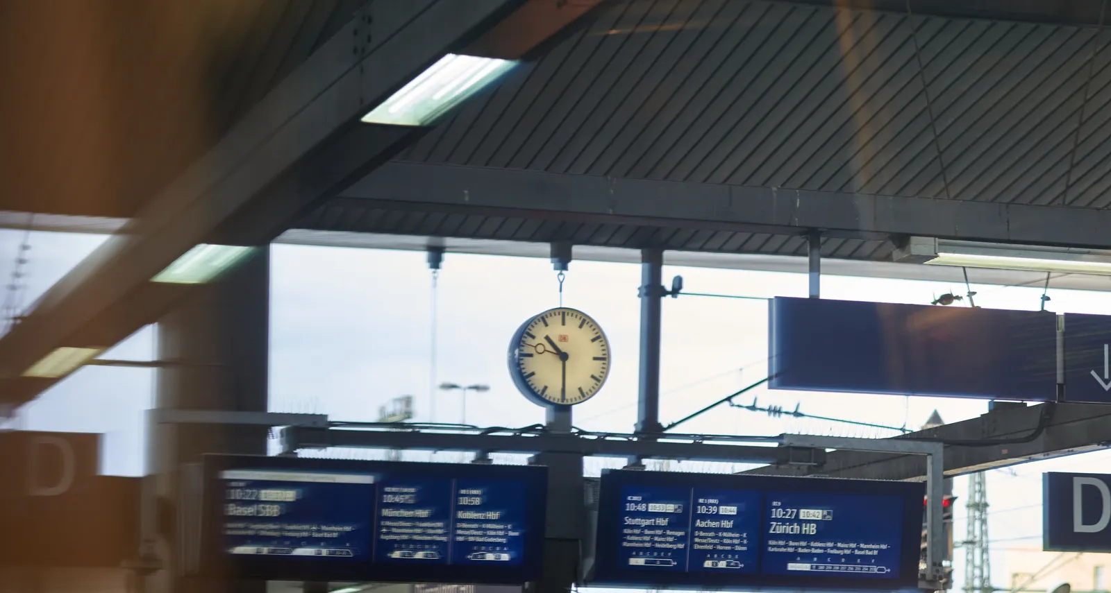 A blurry image of a train station. While the clock is blurry as well, you can still see that it is half past 10.