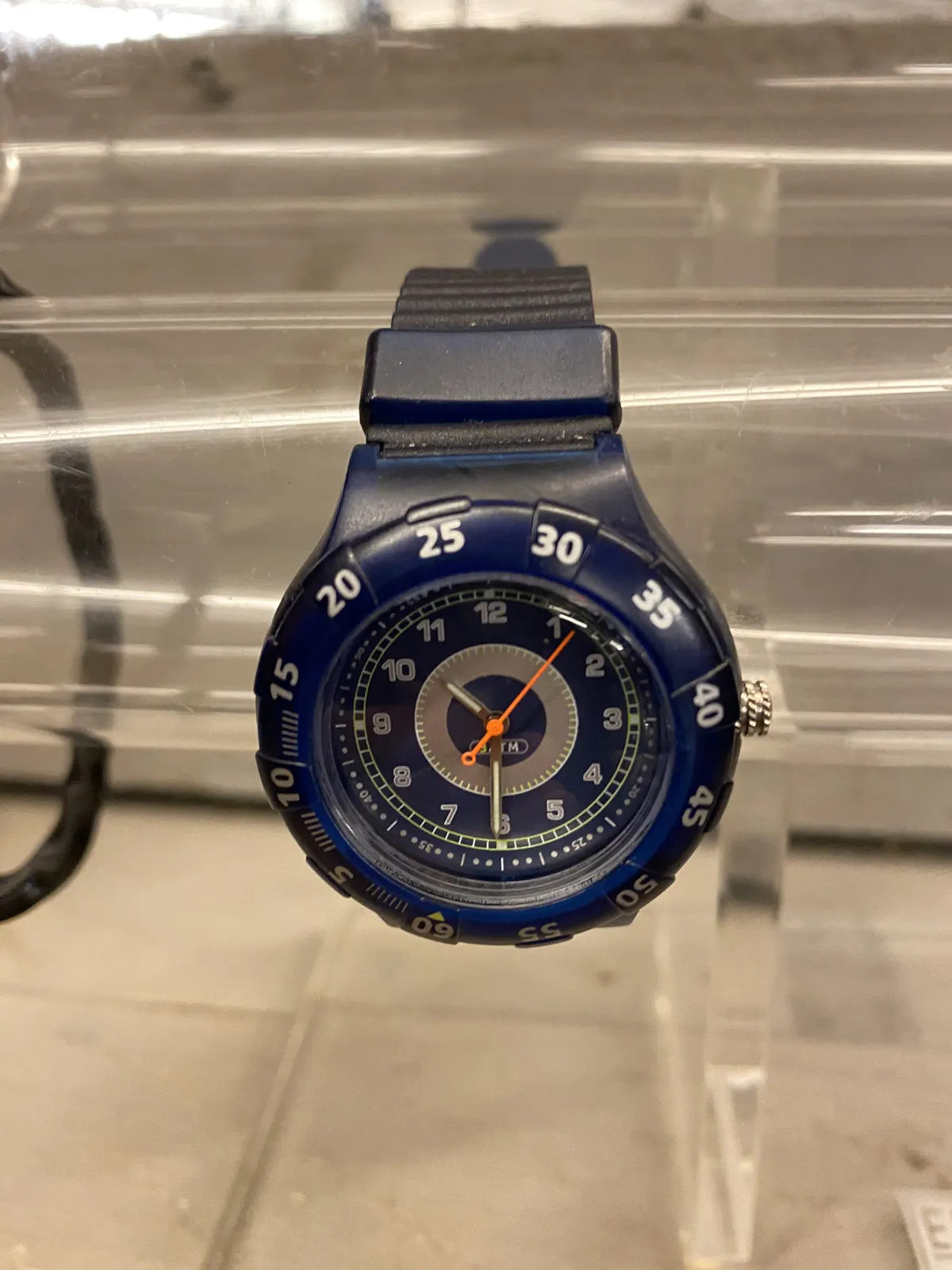 A wrist watch on a glass plate. It points at half past 10.
