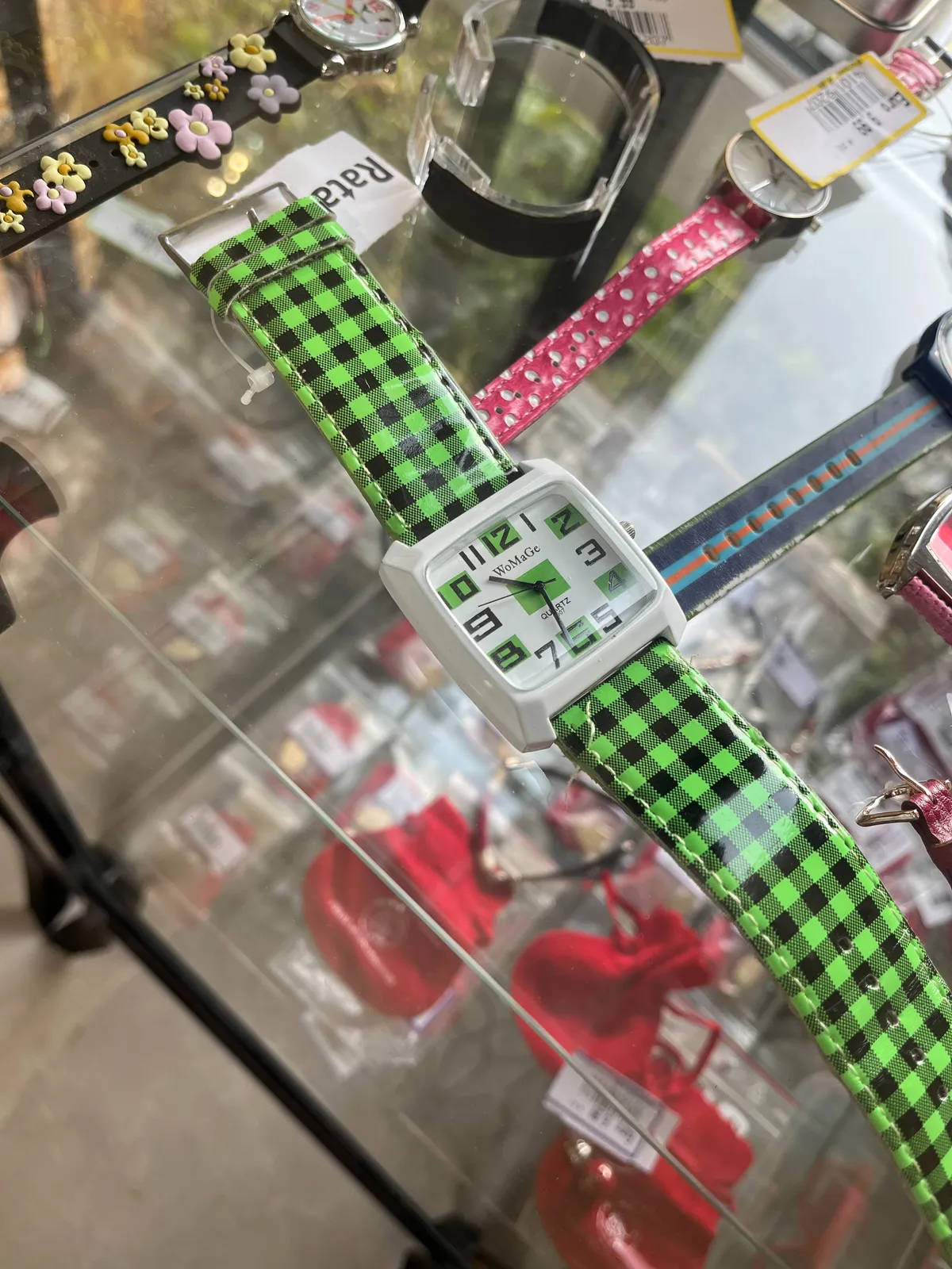 A bright green wrist watch on display. It bears the moniker Wo Ma Ge. And it points at 31 minutes past ten.