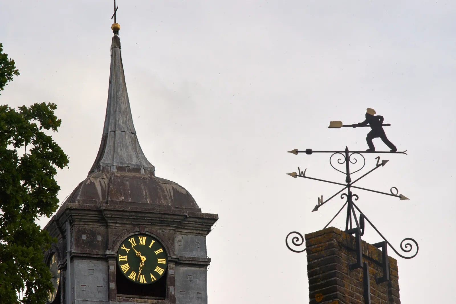 There’s a wind vane with a figure of a baker on it. It points in the direction of an old tower with a clock on it. According to the clock it is 32 past 10.