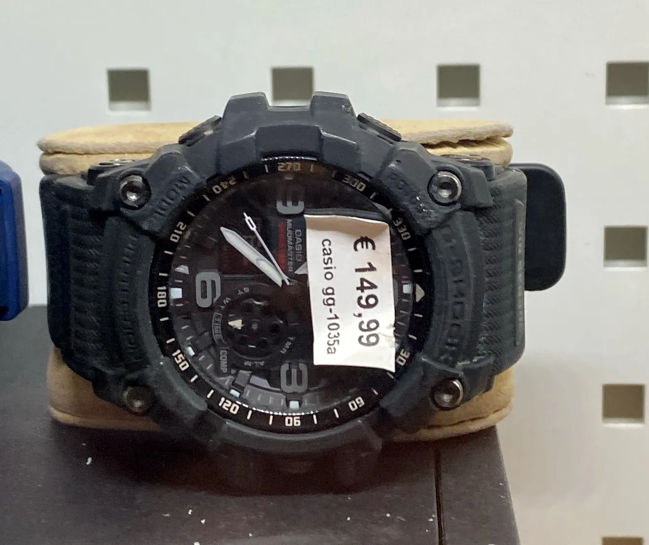 A Casio Mudmaster. A big and clunky watch. It points at 23 minutes to 11.