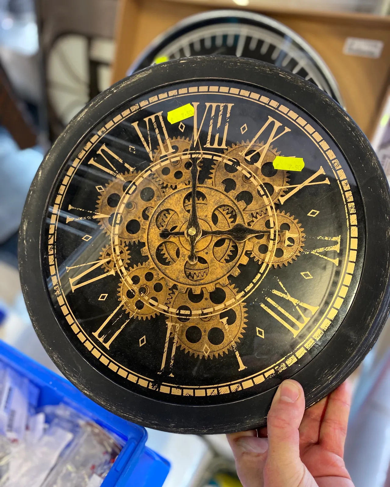 Someone is holding a clock in their hand. They didn’t take the trouble to hold it upright which makes it hard to see that it points at 22 minutes to 11.