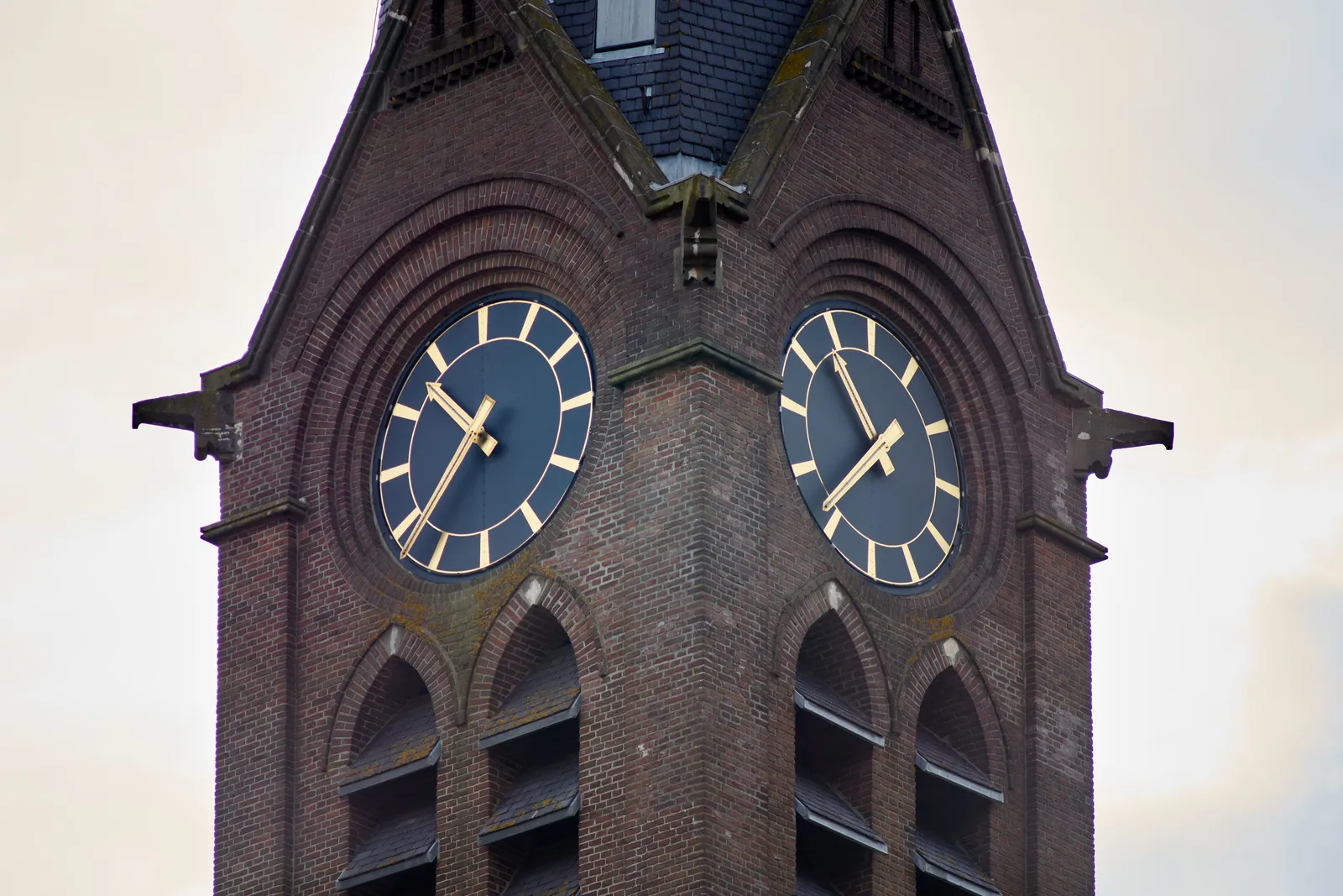 Two clocks on a church tower. One of them points at 22 minutes to 11.