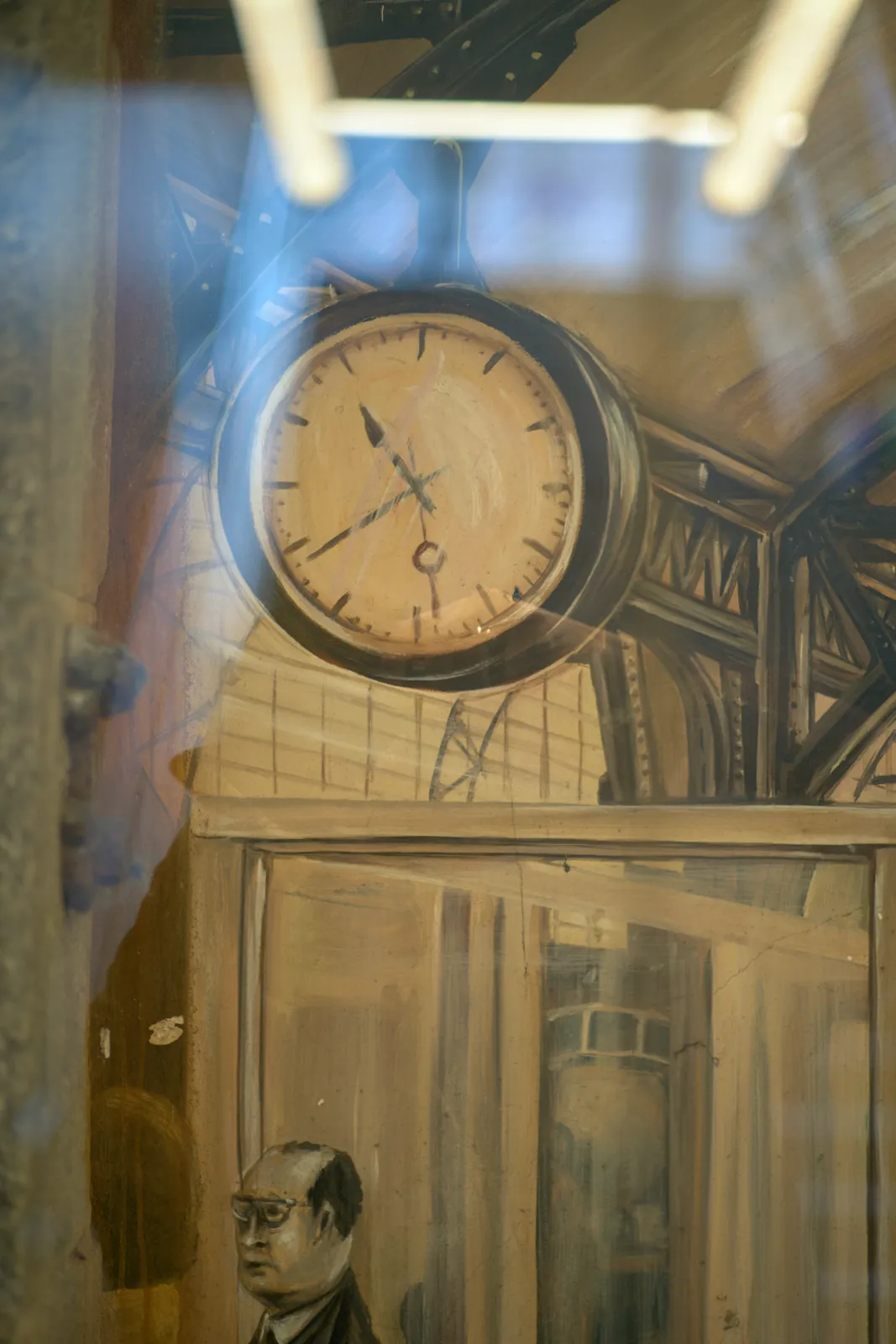 A detail of a painting with a person, a train, a construction, and a clock that points at 21 minutes to eleven.