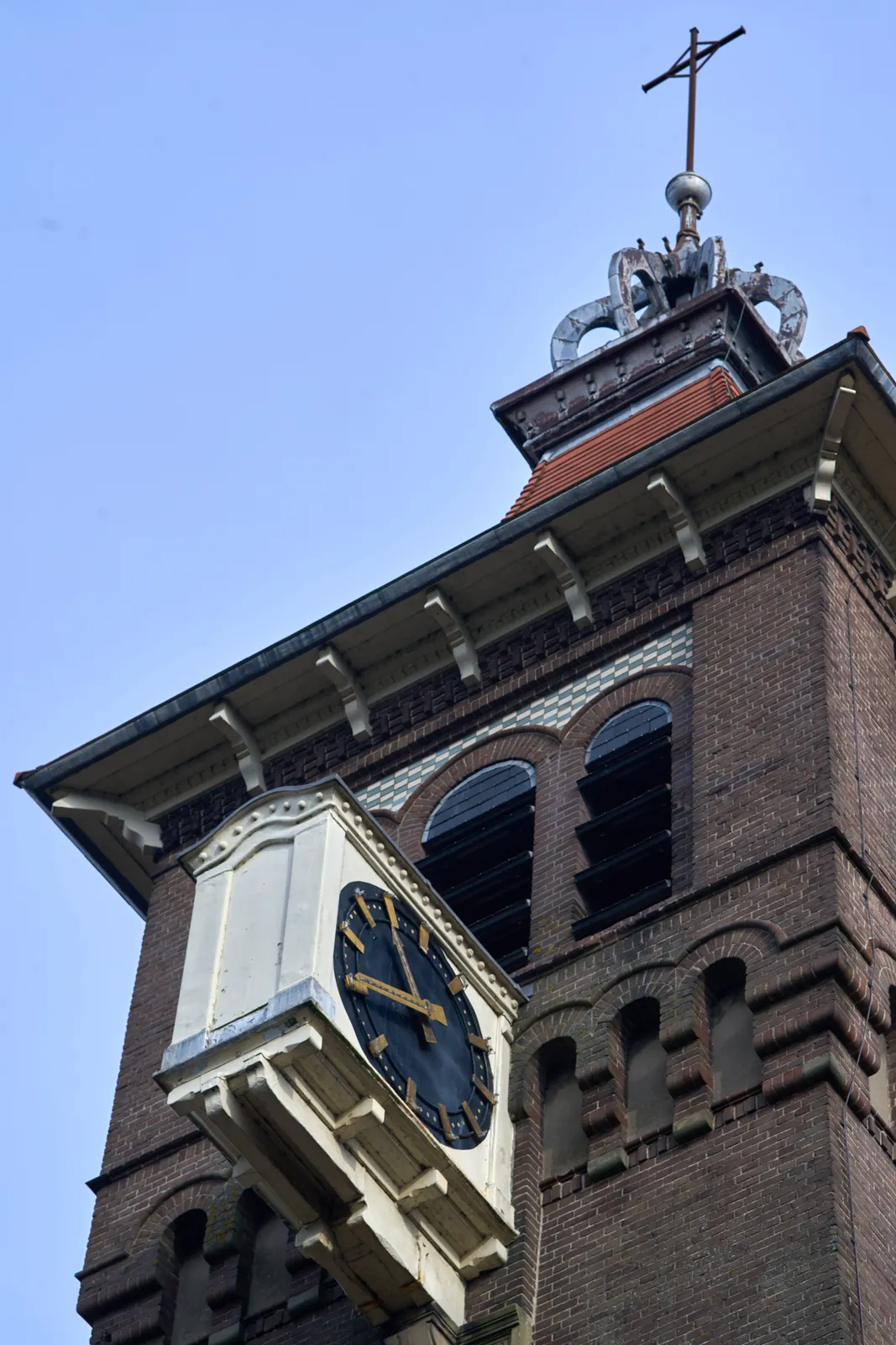 Looking up at a brick church tower with a clock that, strangely, sticks out of the wall. This clock points at 20 to 11.