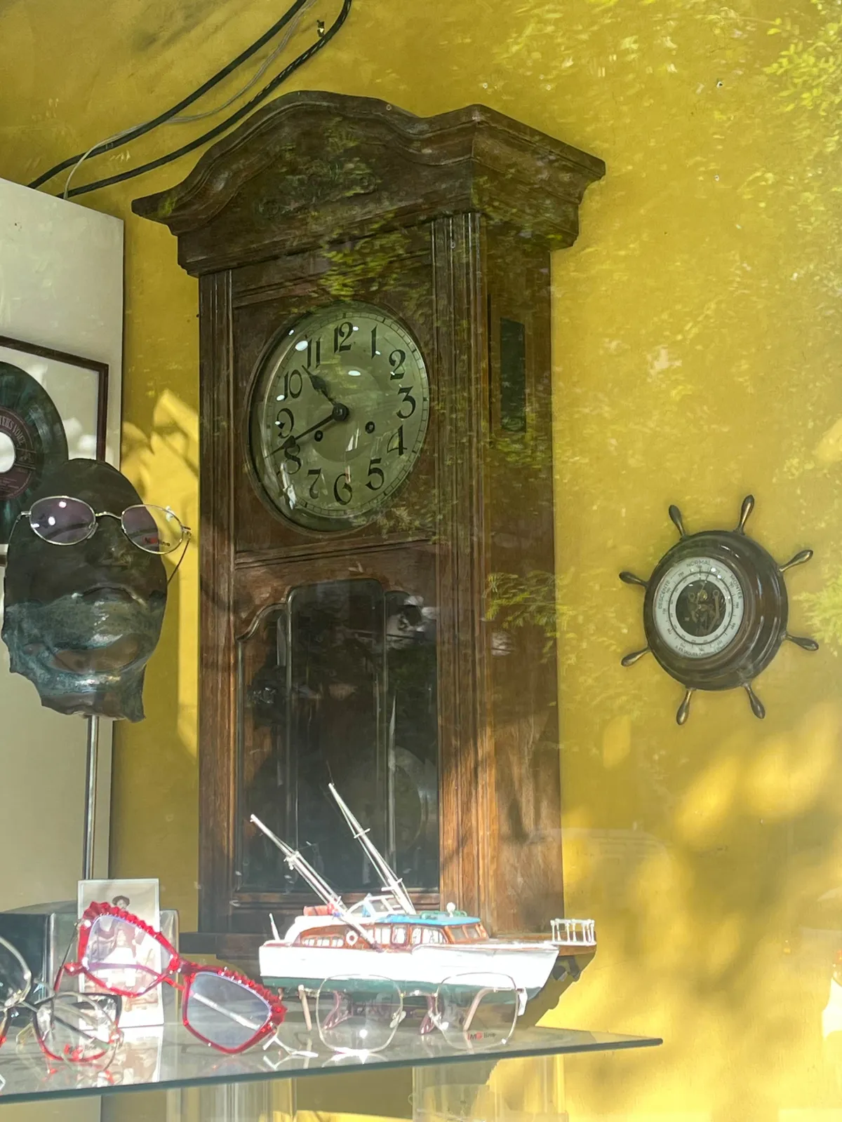 An old clock on a wall in an opticians store. It points at 18 minutes to eleven.