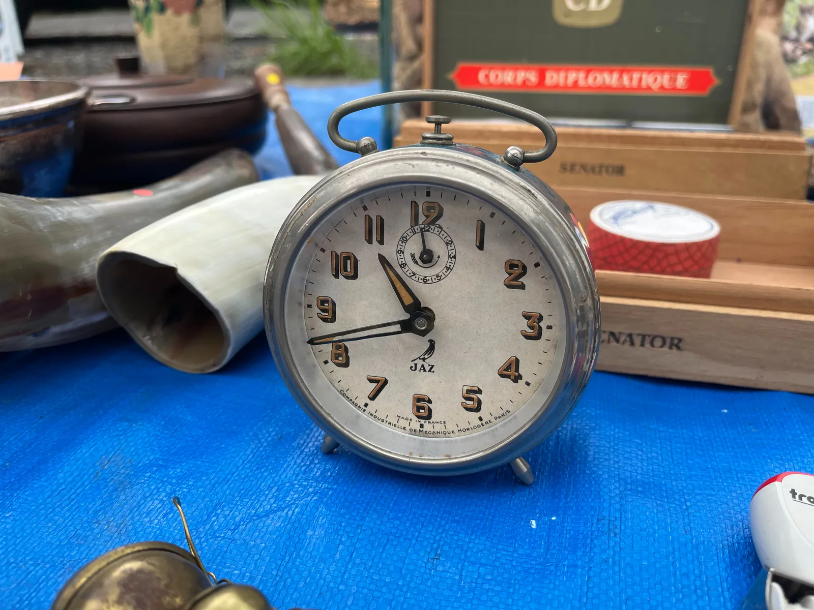 A nice old alarm clock, with well designed hands. The numbers are golden, with black shadows. The word Jaz is printed on its face with a bird over it. It also says, in small print at the bottom, that it’s made in France by Compagnie Industrielle de Mecanique Horlogere, in Paris. This alarm clock points at 42 minutes past 10.