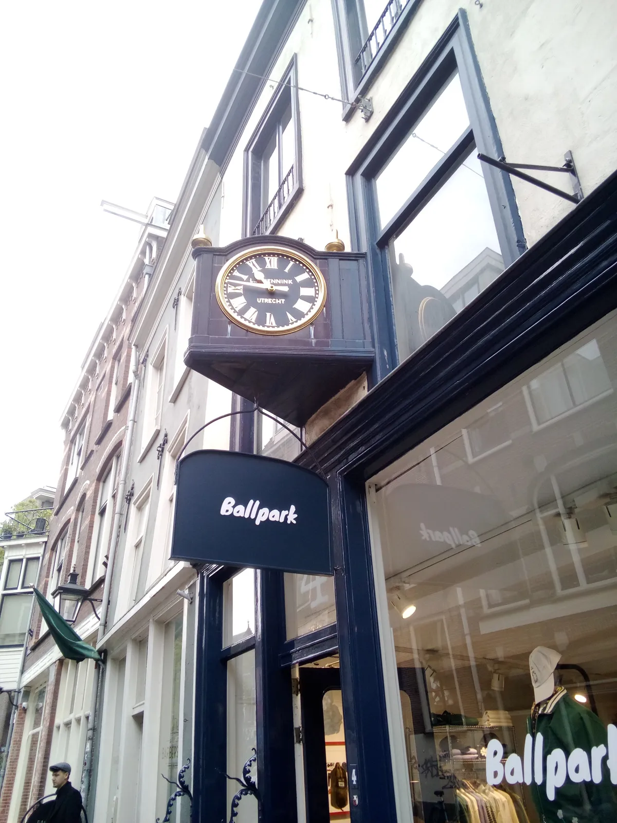 Above a shopping window there’s an old clock that points at 13 minutes to eleven.