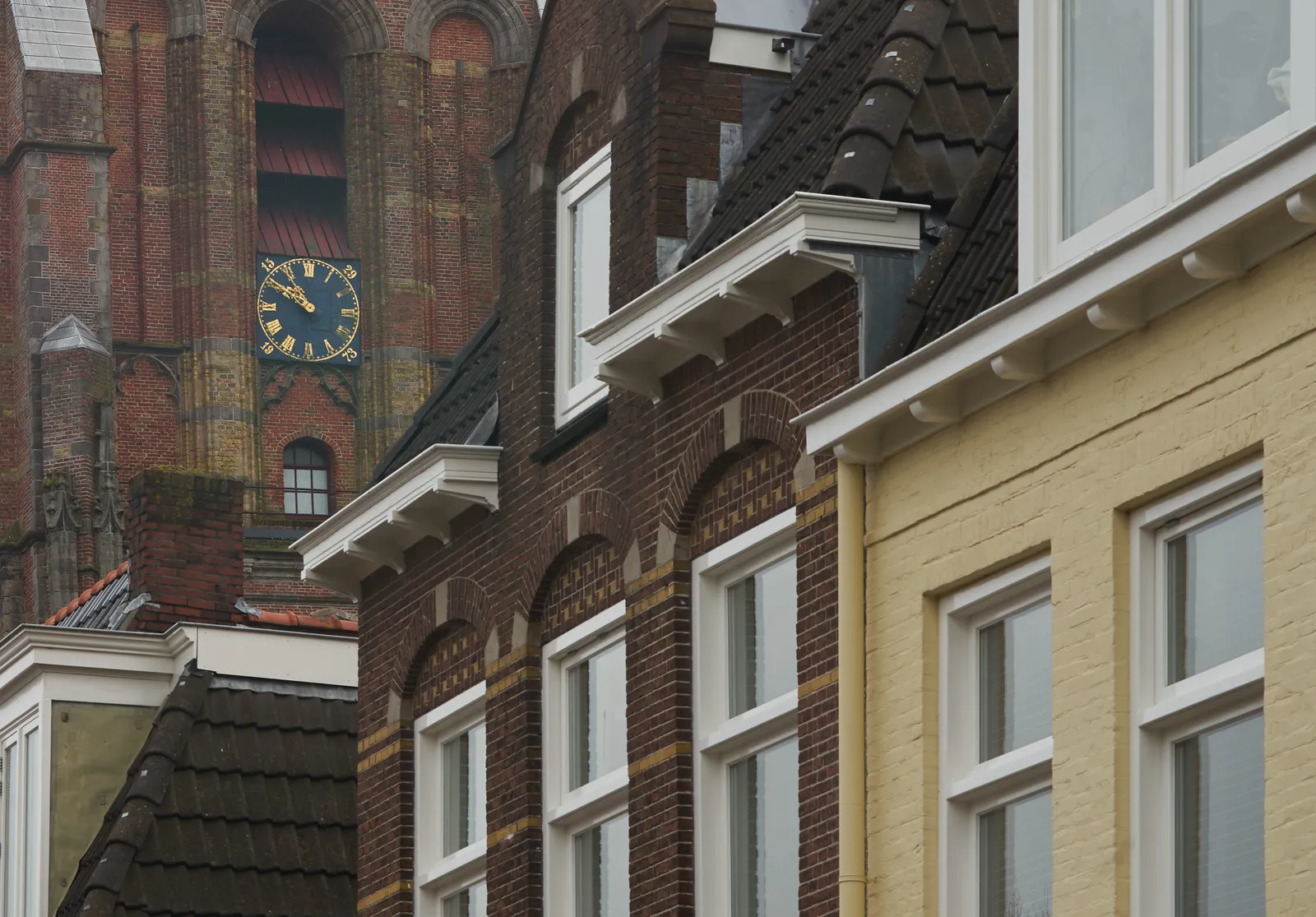 A few houses in the foreground, and a large church tower in the background. According to the clock on this tower it is 9 minutes to 11.