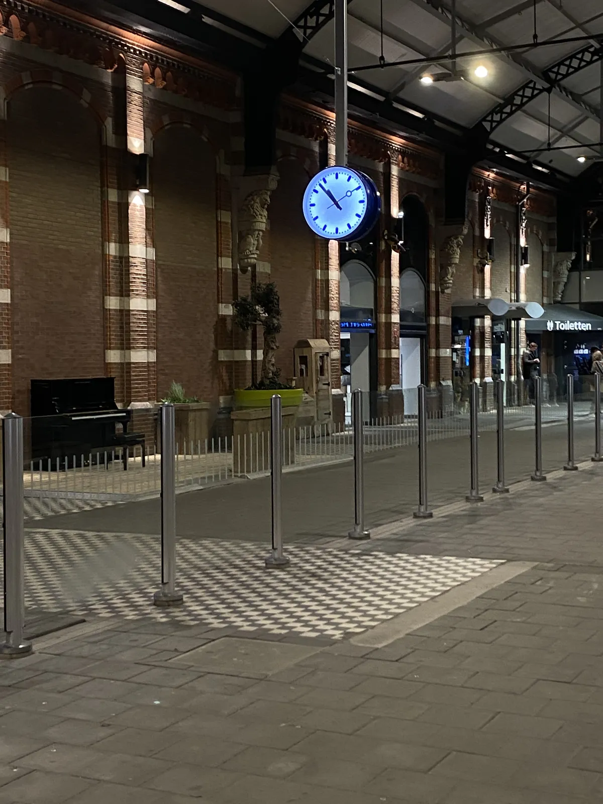 A clock somewhere in an empty Dutch station. It points at 7 minutes to 11.