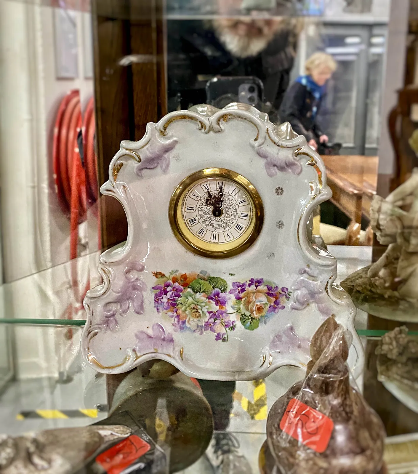 An old, frivolous, porcelain clock. It points at one minute past 11.
