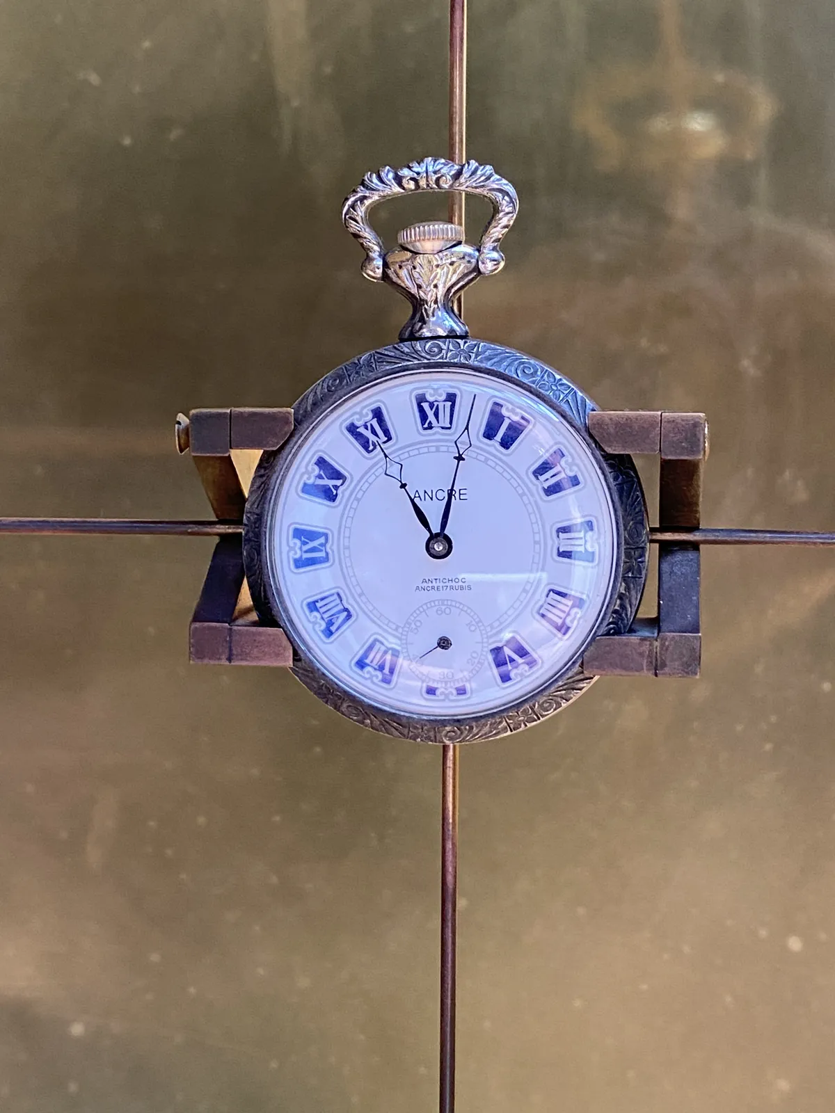 An old hand watch, held my a nice symmetrical mechanism, points at 2 past 11.
