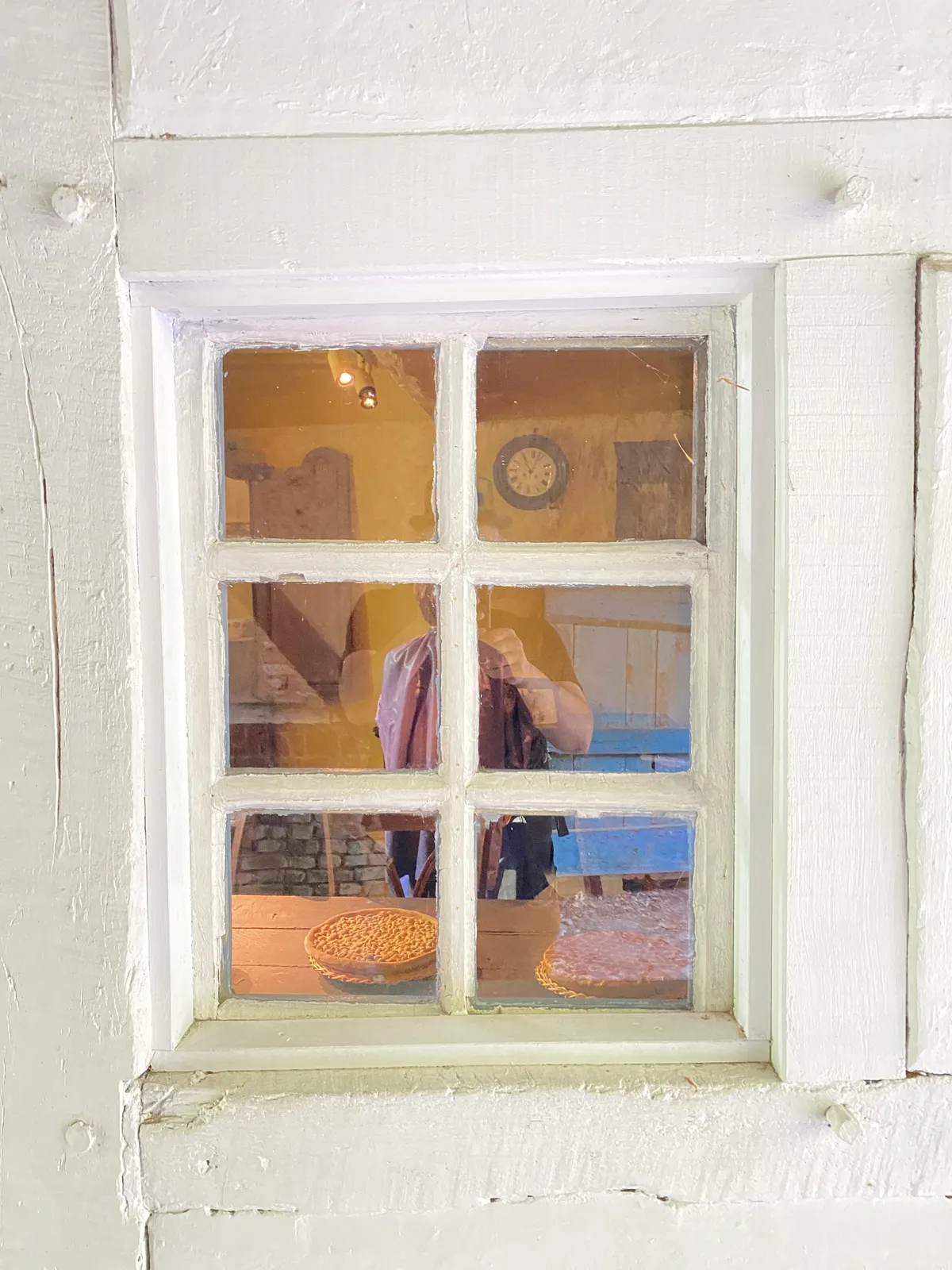 Peeking thru a window. There are cakes on a table and a clock on the wall. It points at 3 past 11.