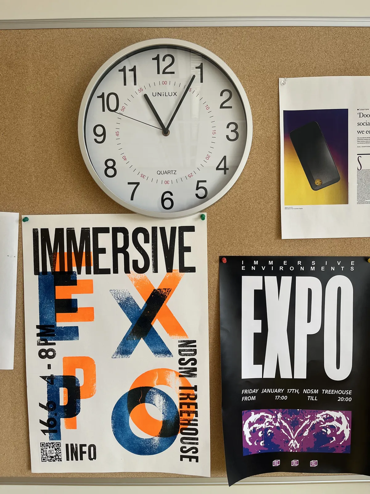 Above two posters promoting exhibitions of immersive work there’s a wall clock that points at 4 minutes past eleven.  