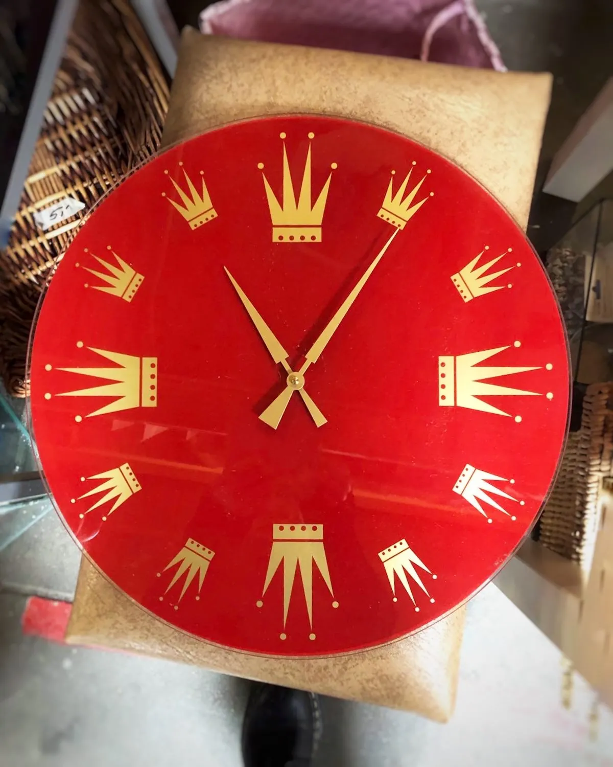 A red clock with golden crowns as hour indicators. It seems to point at 6 past 11.