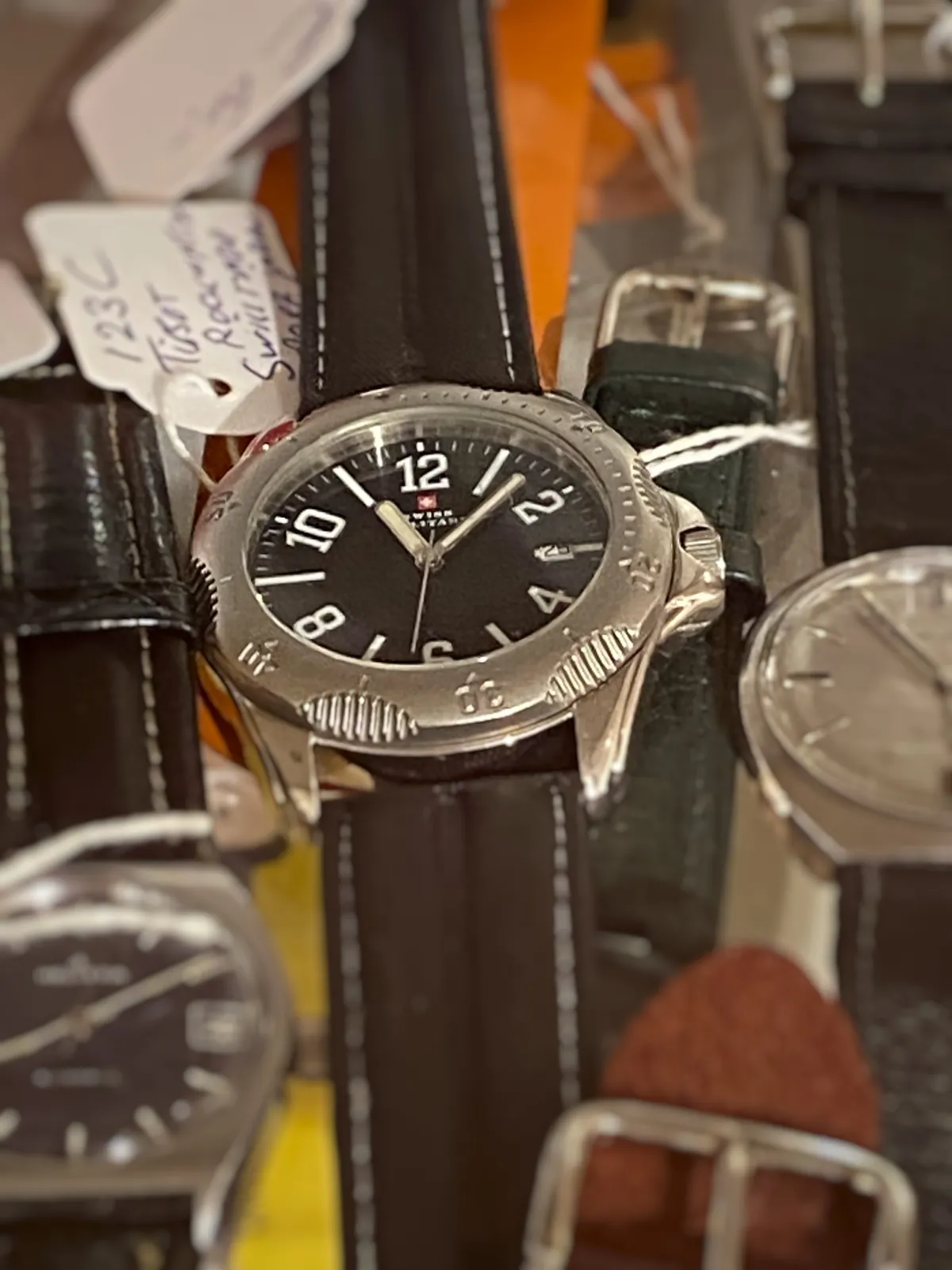 A few wrist watches, only one of them is in focus. It points at 7 minutes past 11.