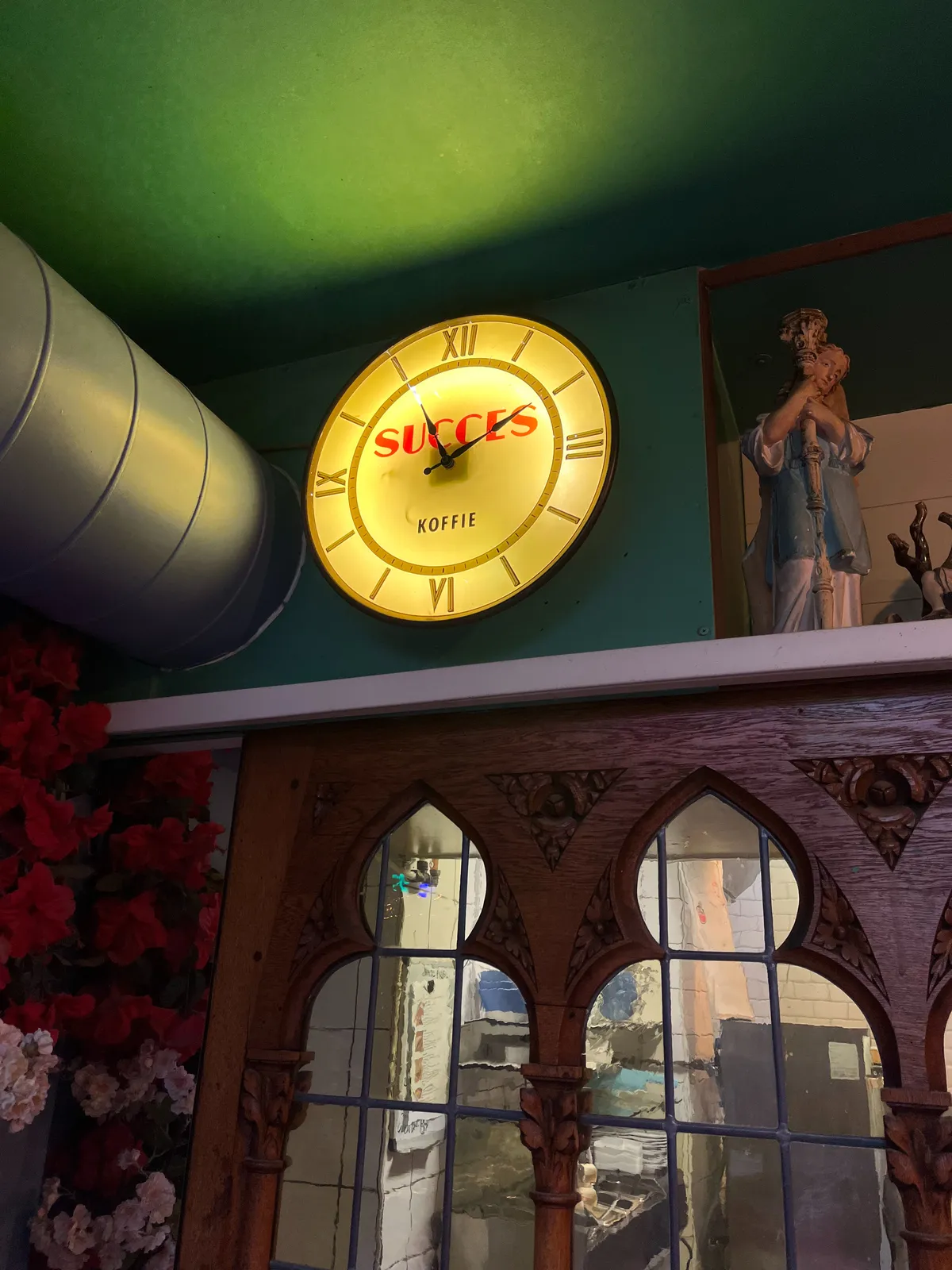 In an eclectic environment there’s a bright yellow clock with the words succes koffie on it. It points at 9 past 11.