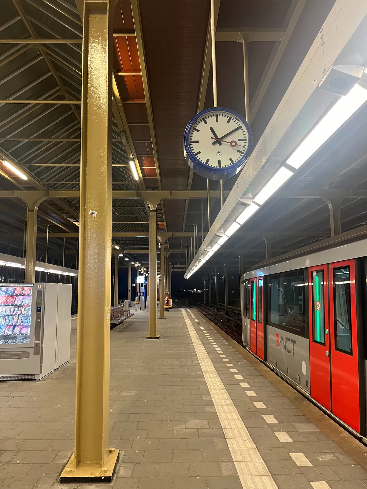 A older station clock on an Amsterdam metro platform. It points at 10 past 11.